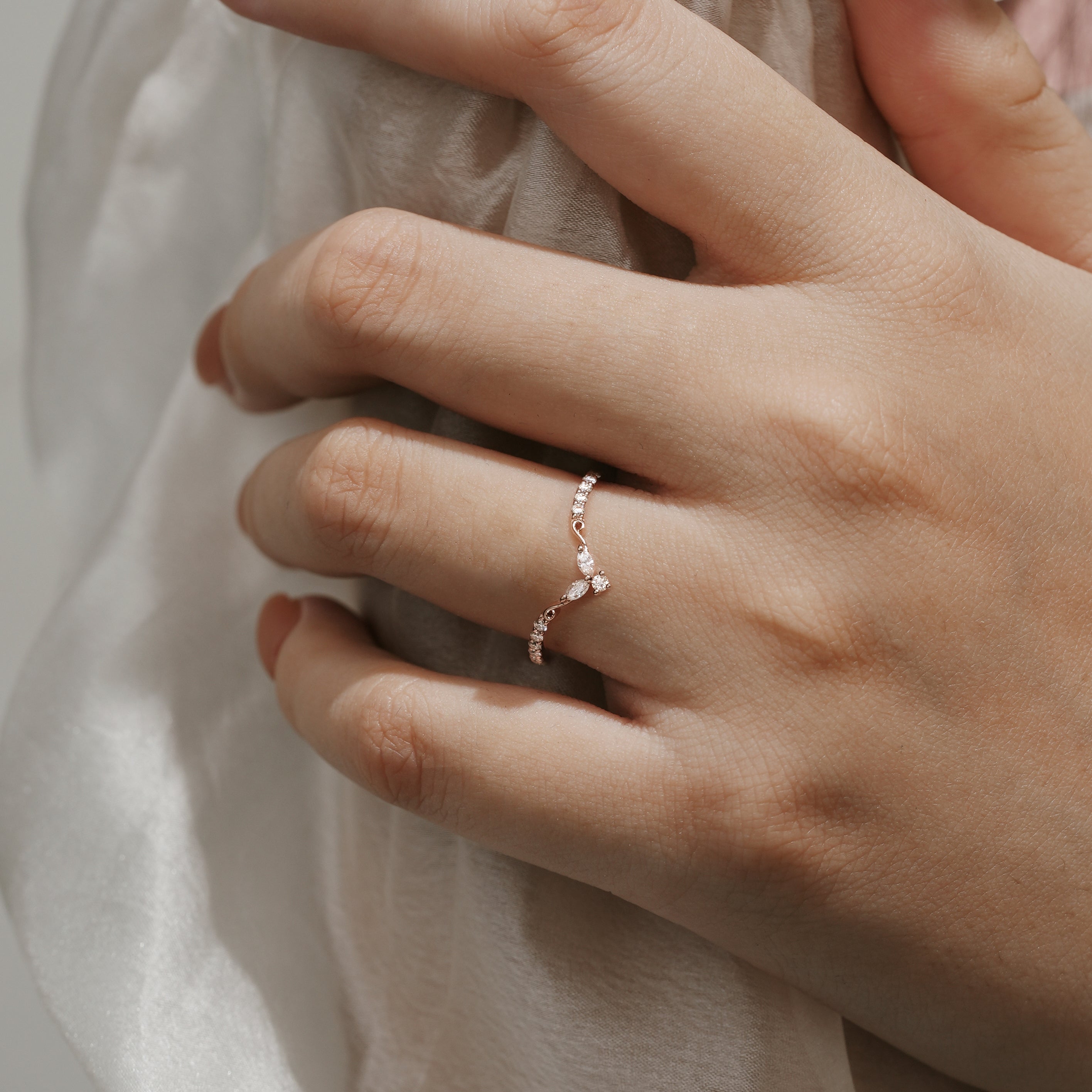 Rose gold V-shaped moissanite wedding band on hand