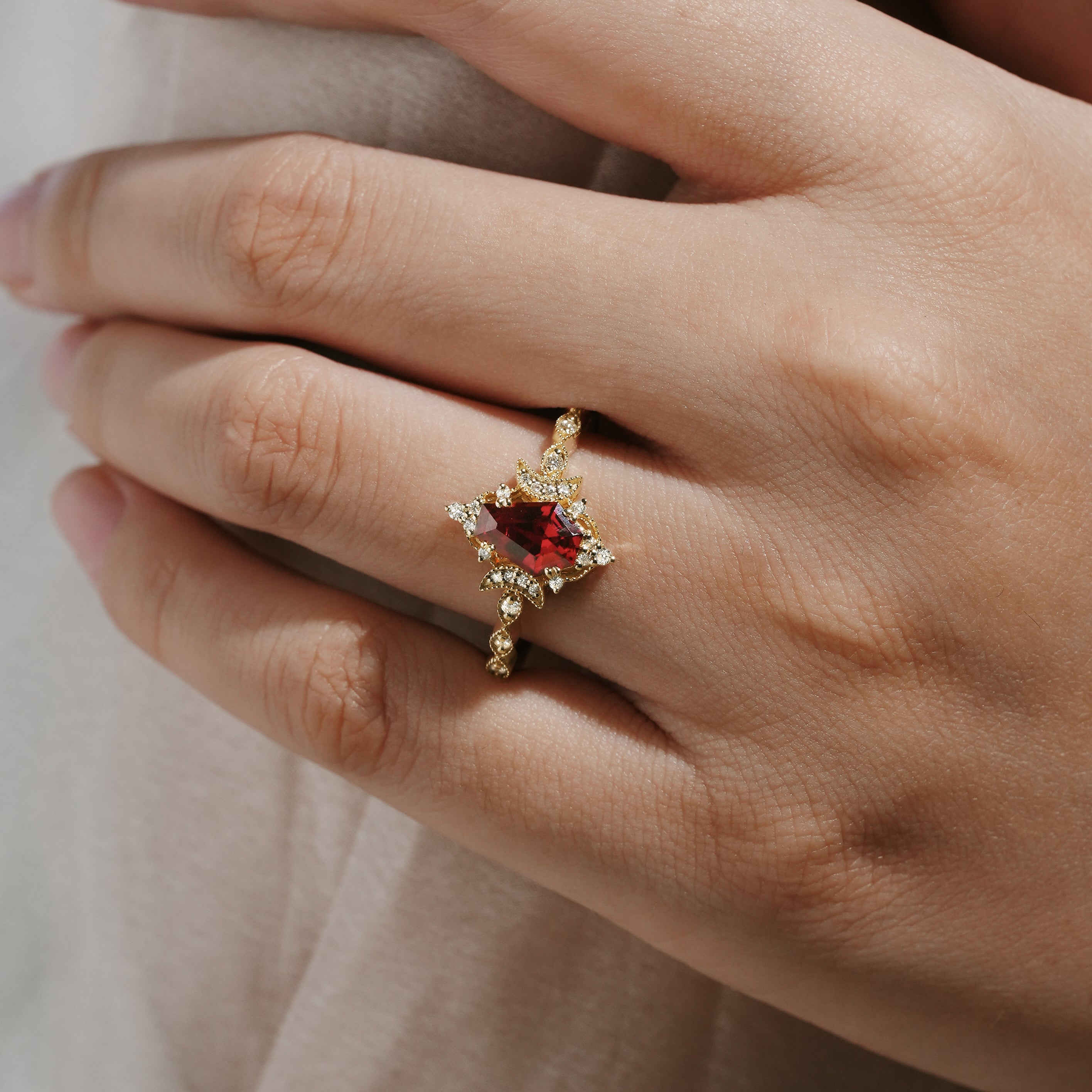 Yellow gold engagement ring featuring a coffin-cut lab grown ruby and moissanite accents, set against a hand.