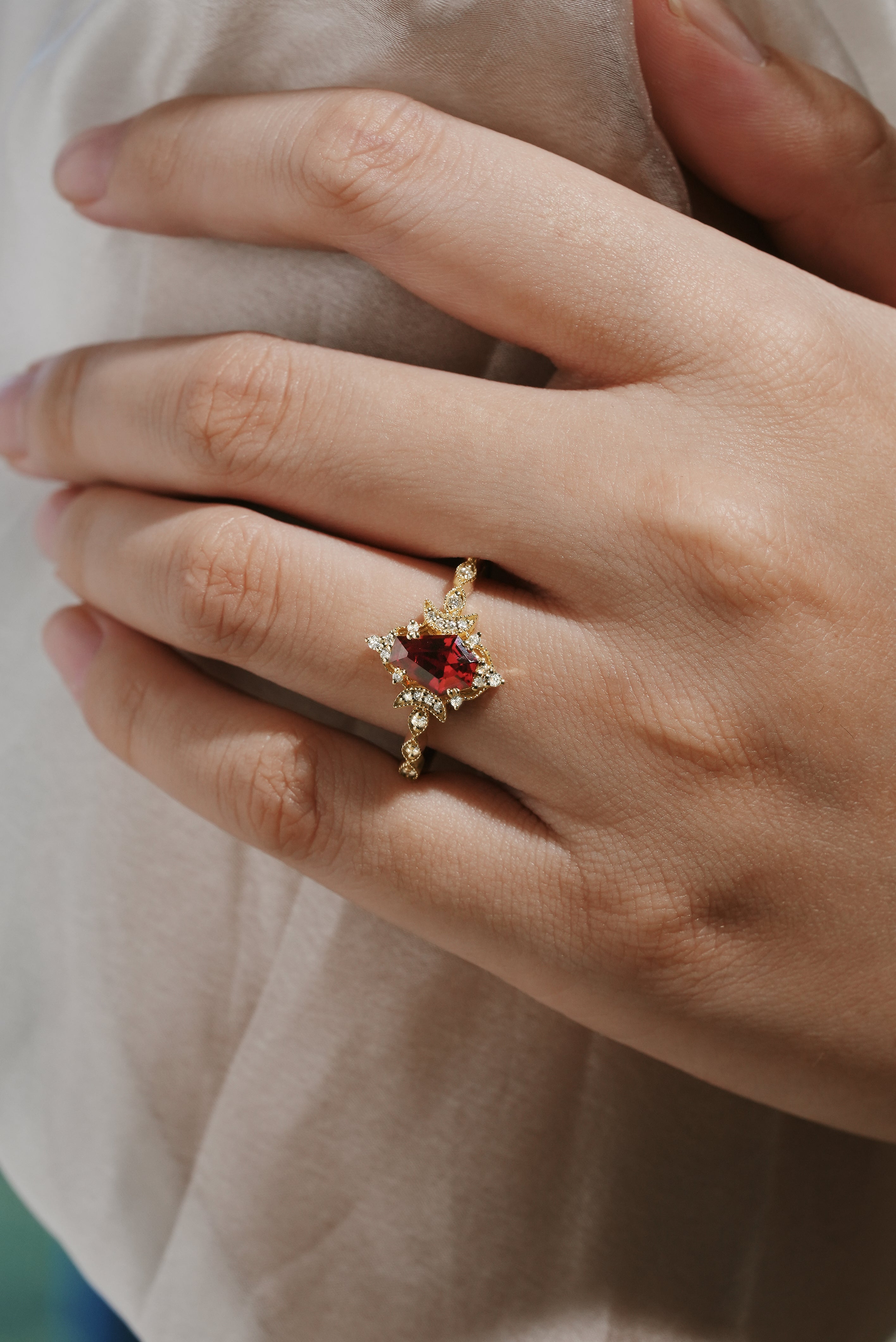 Yellow gold engagement ring featuring a coffin-cut lab grown ruby and moissanite accents, set against a hand.
