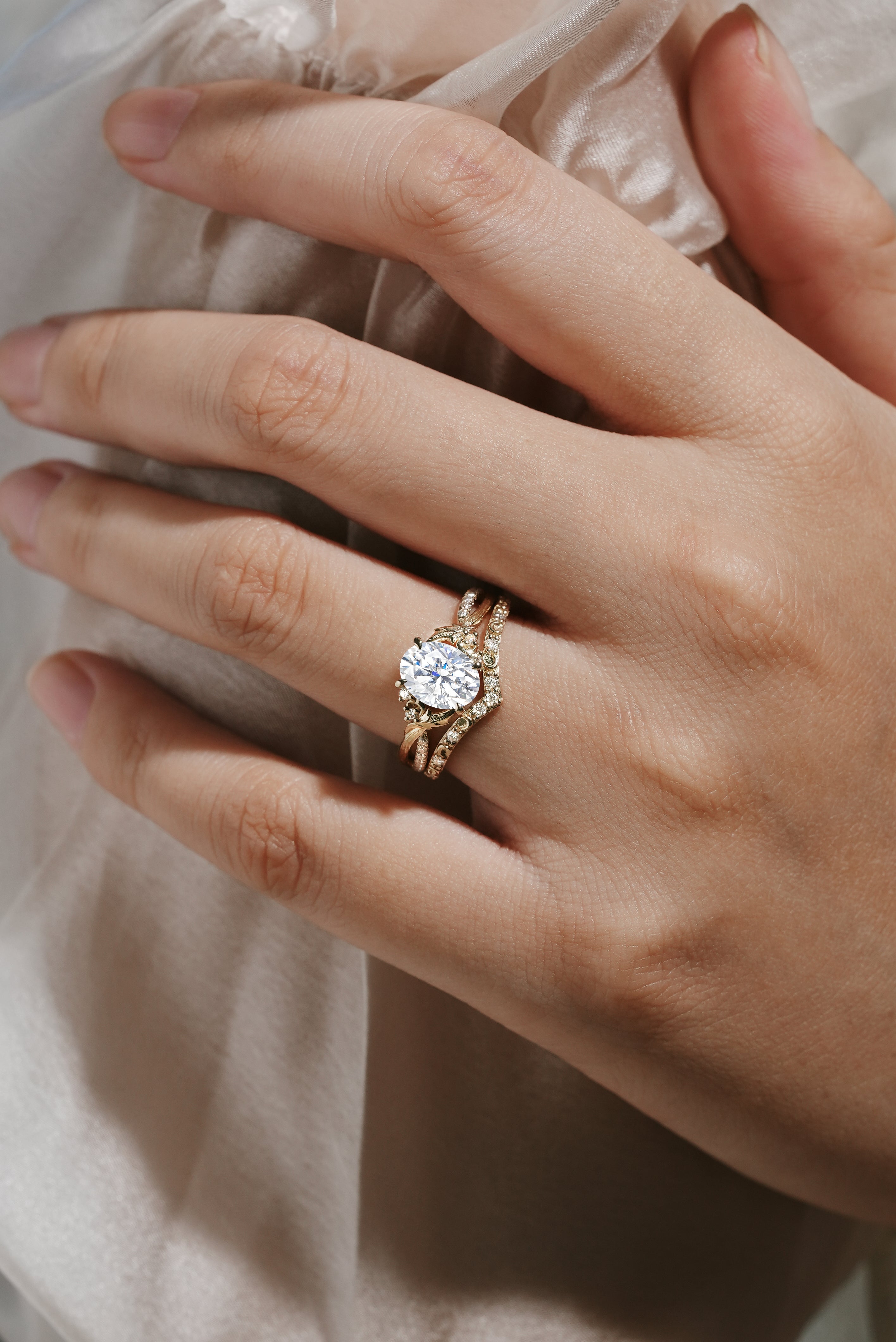 Moissanite leaf engagement ring set with a bark texture and V-shaped wedding band, on a hand.