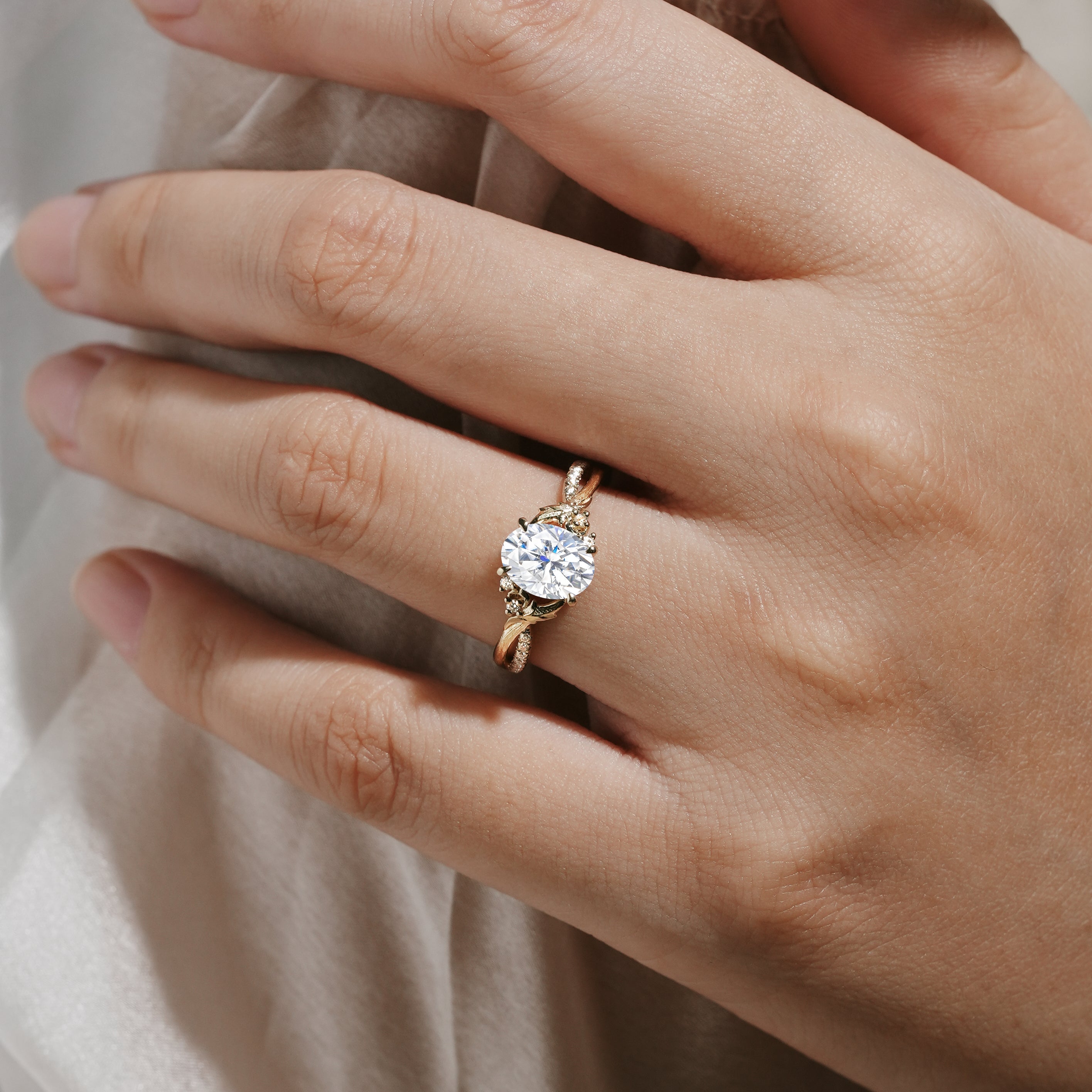 Oval moissanite engagement ring with leaf and bark design on a hand, Lahela Jewelry.