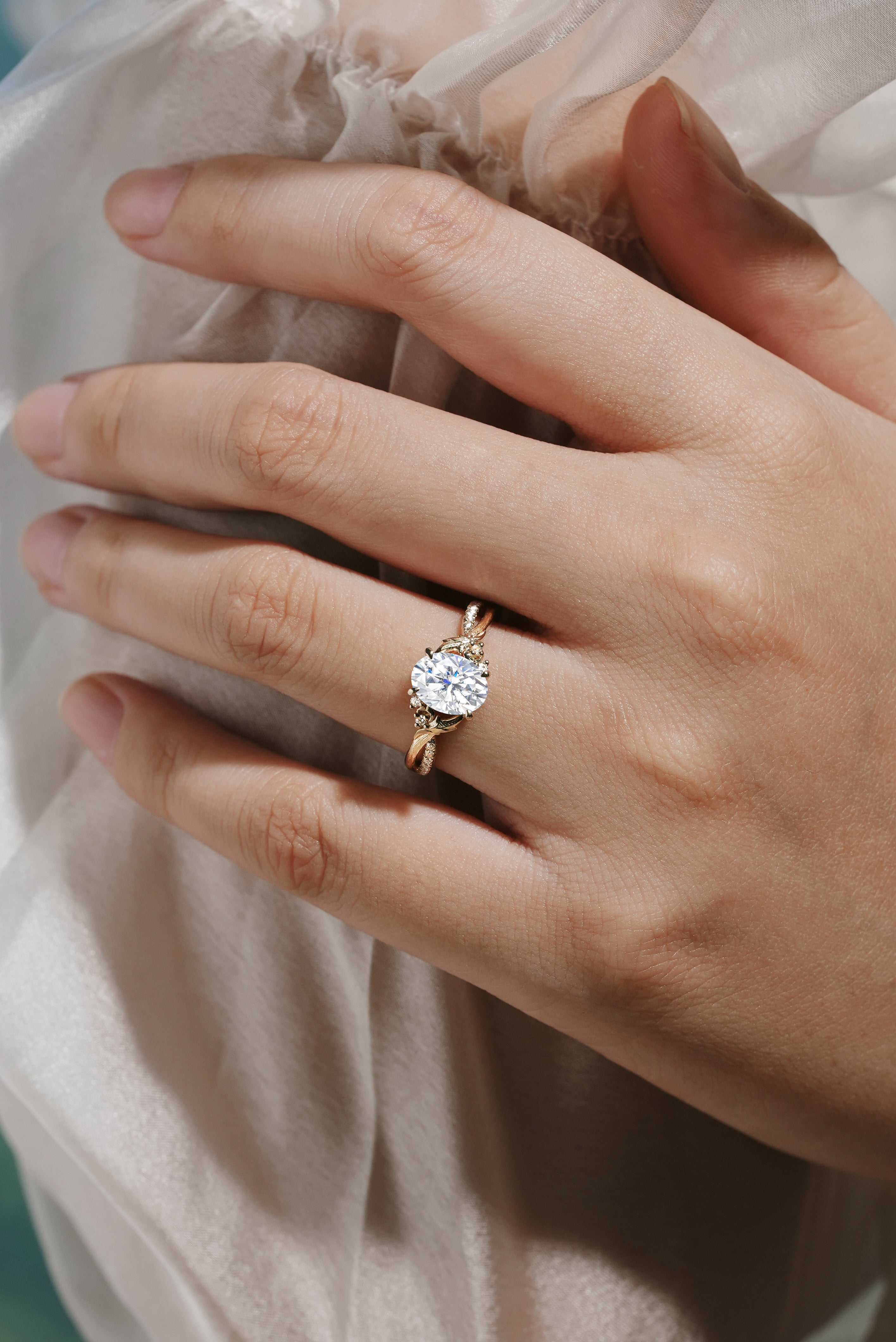 Oval moissanite engagement ring with leaf and bark design on a hand, Lahela Jewelry.