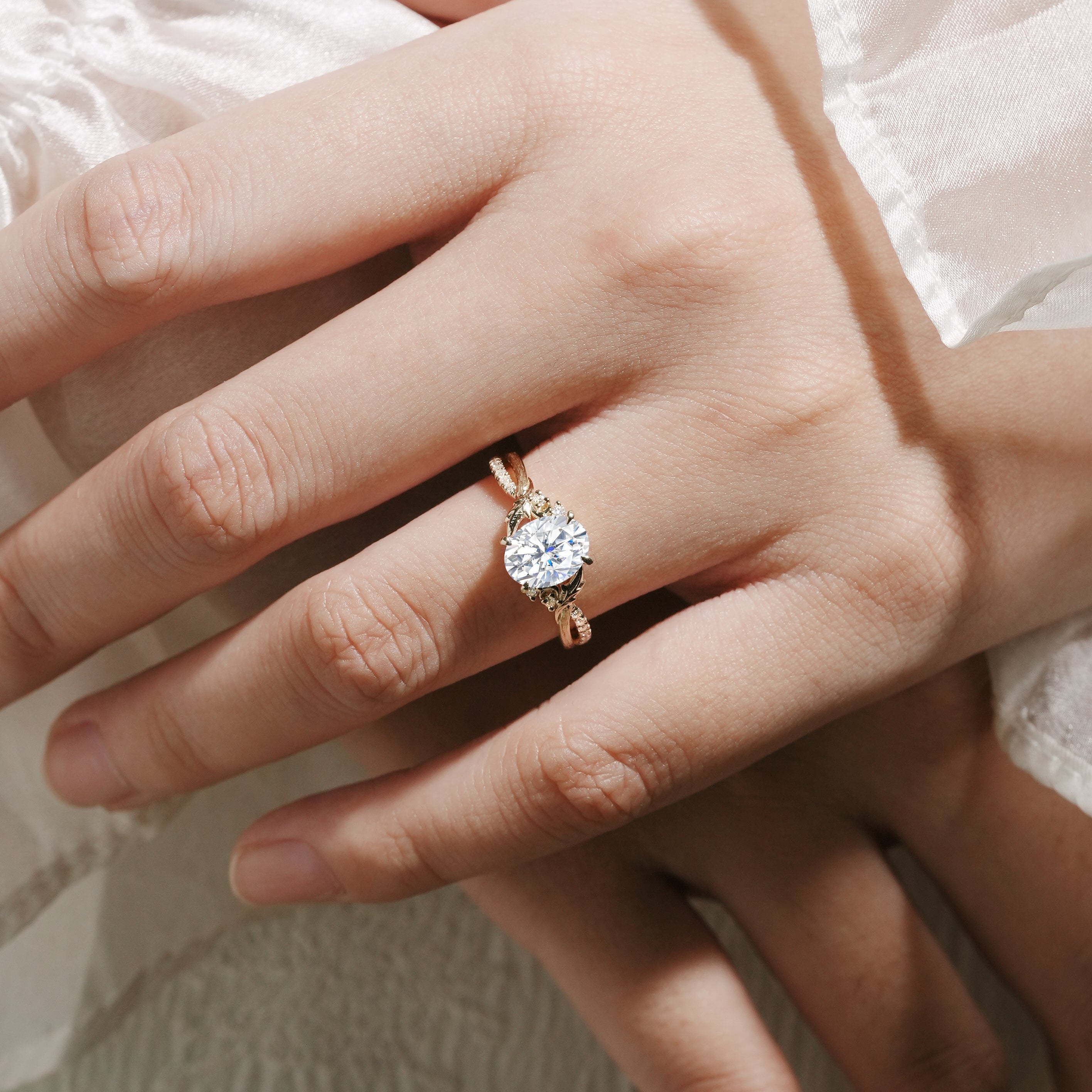 Oval moissanite engagement ring in yellow gold. Features leaf and bark band, bridal jewelry. Handmade detail.