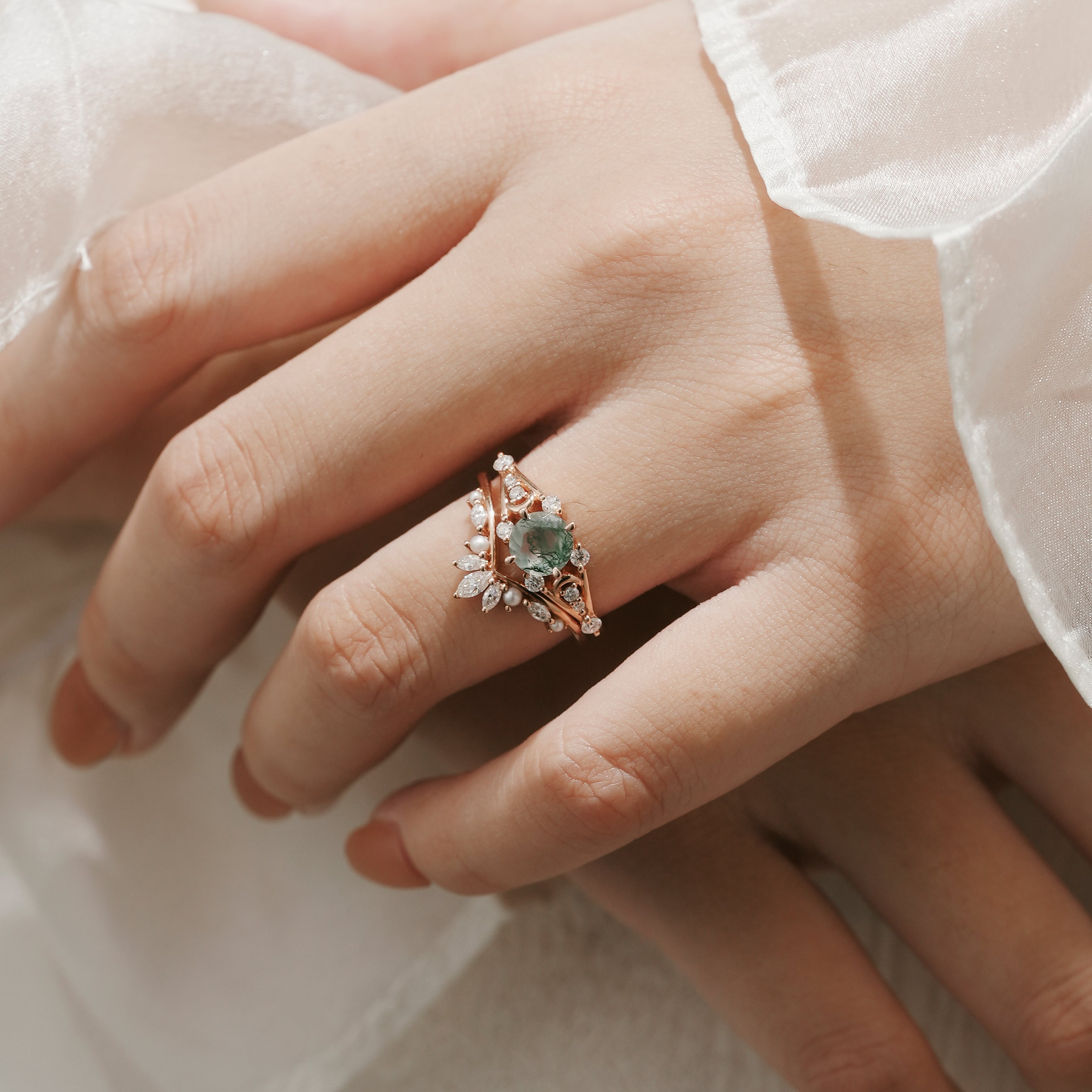 Woman's hand wearing moss agate moon engagement ring