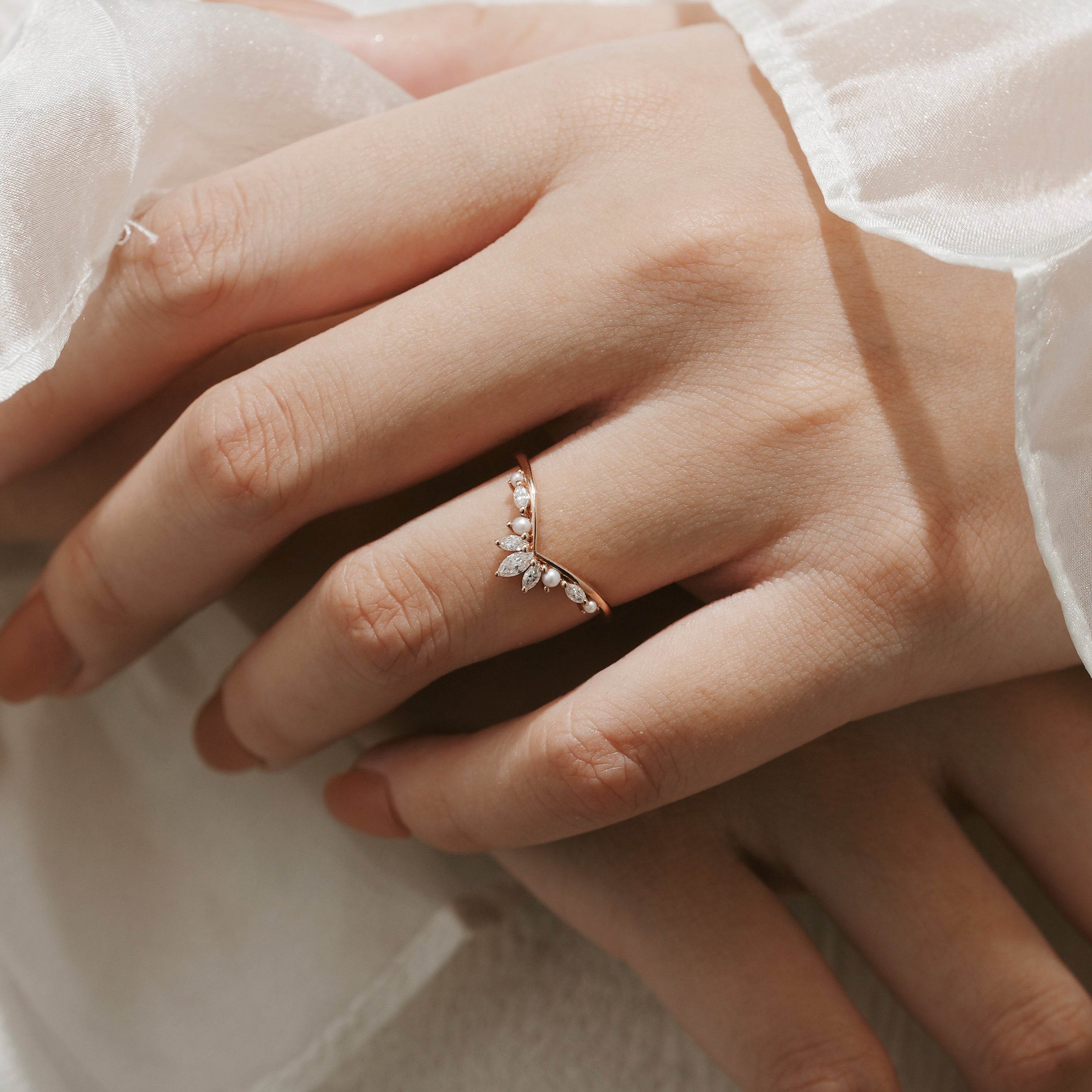 Rose gold curved moissanite and pearl wedding band on a hand