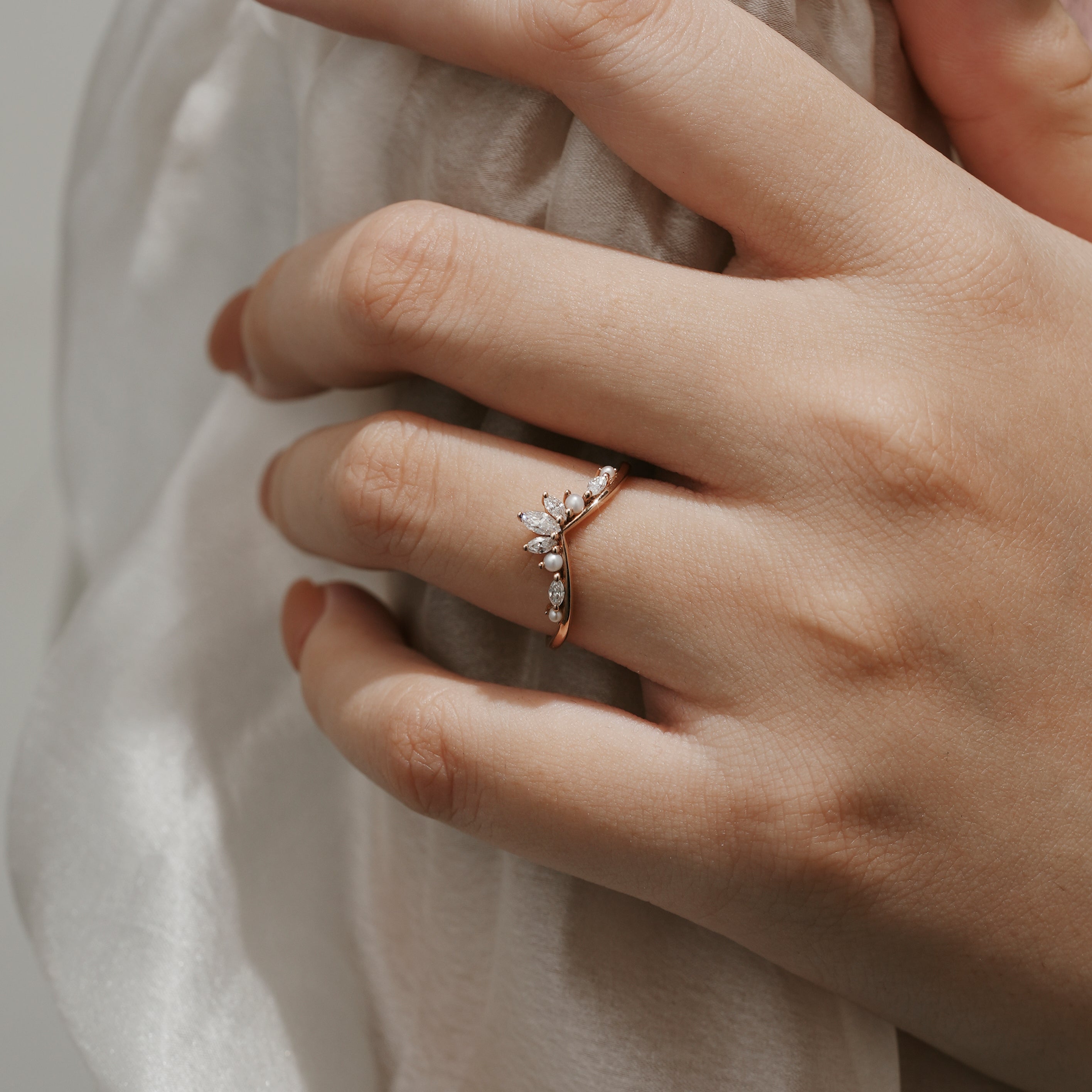 Rose gold curved moissanite and pearl wedding band on a hand