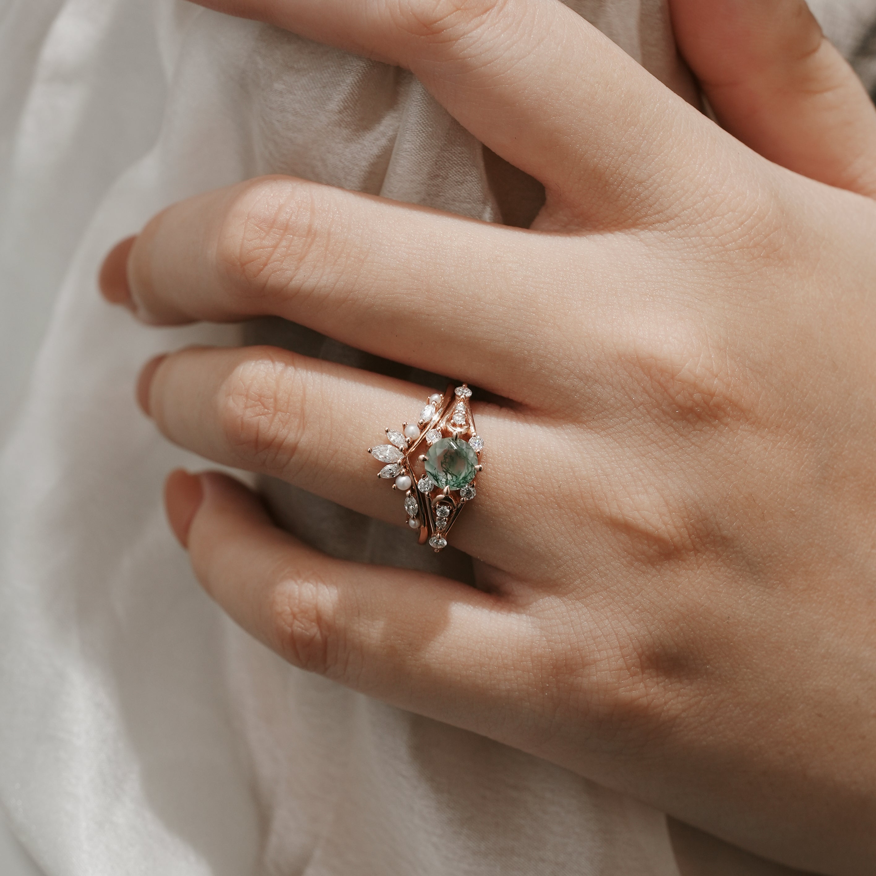 Woman's hand wearing Moss Agate moon engagement ring and wedding band set