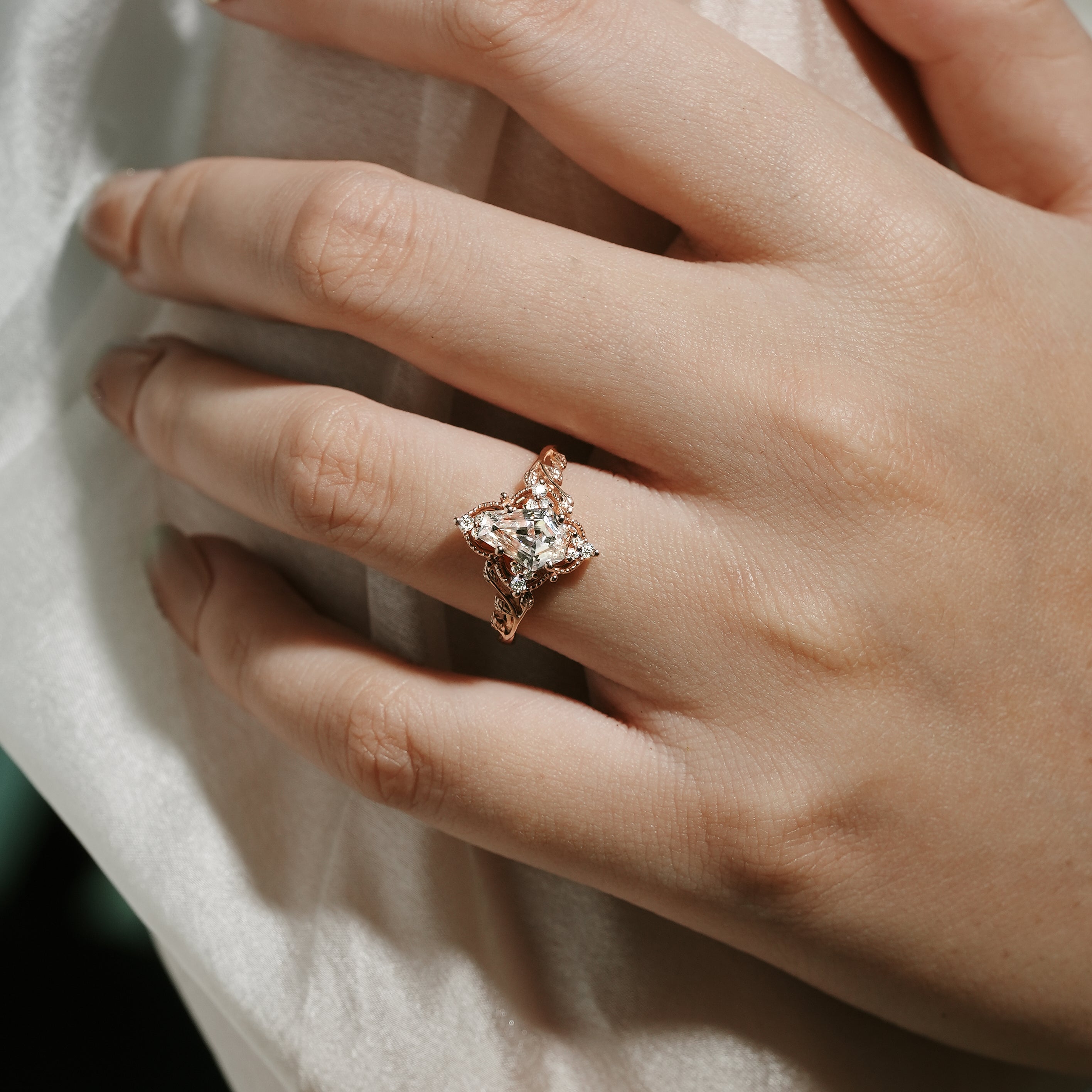 Rose gold leaf engagement ring with coffin-cut moissanite on a hand