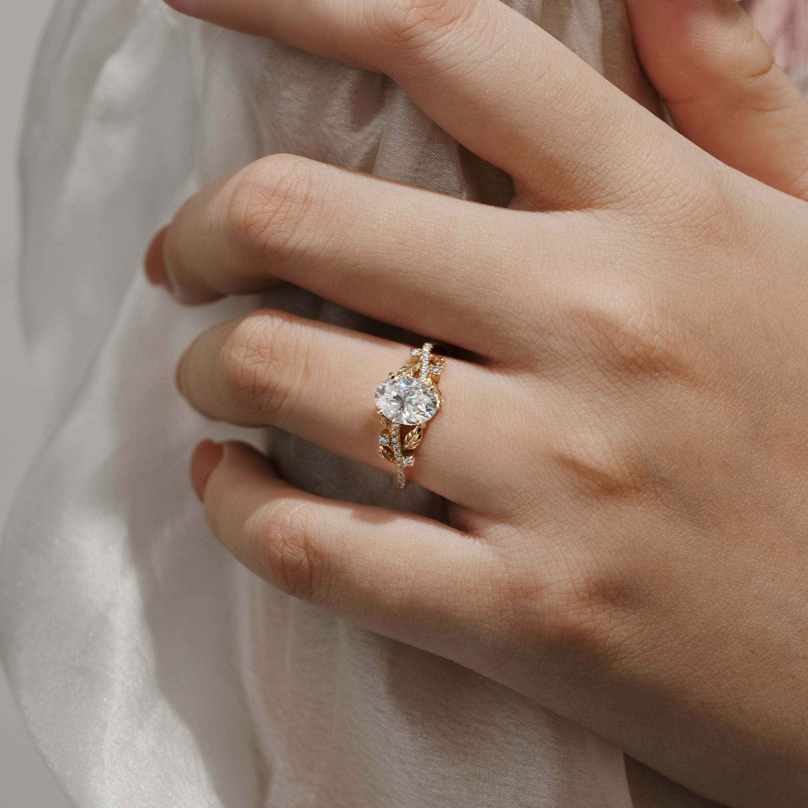 Oval cut moissanite engagement ring with leaf design on a woman's hand