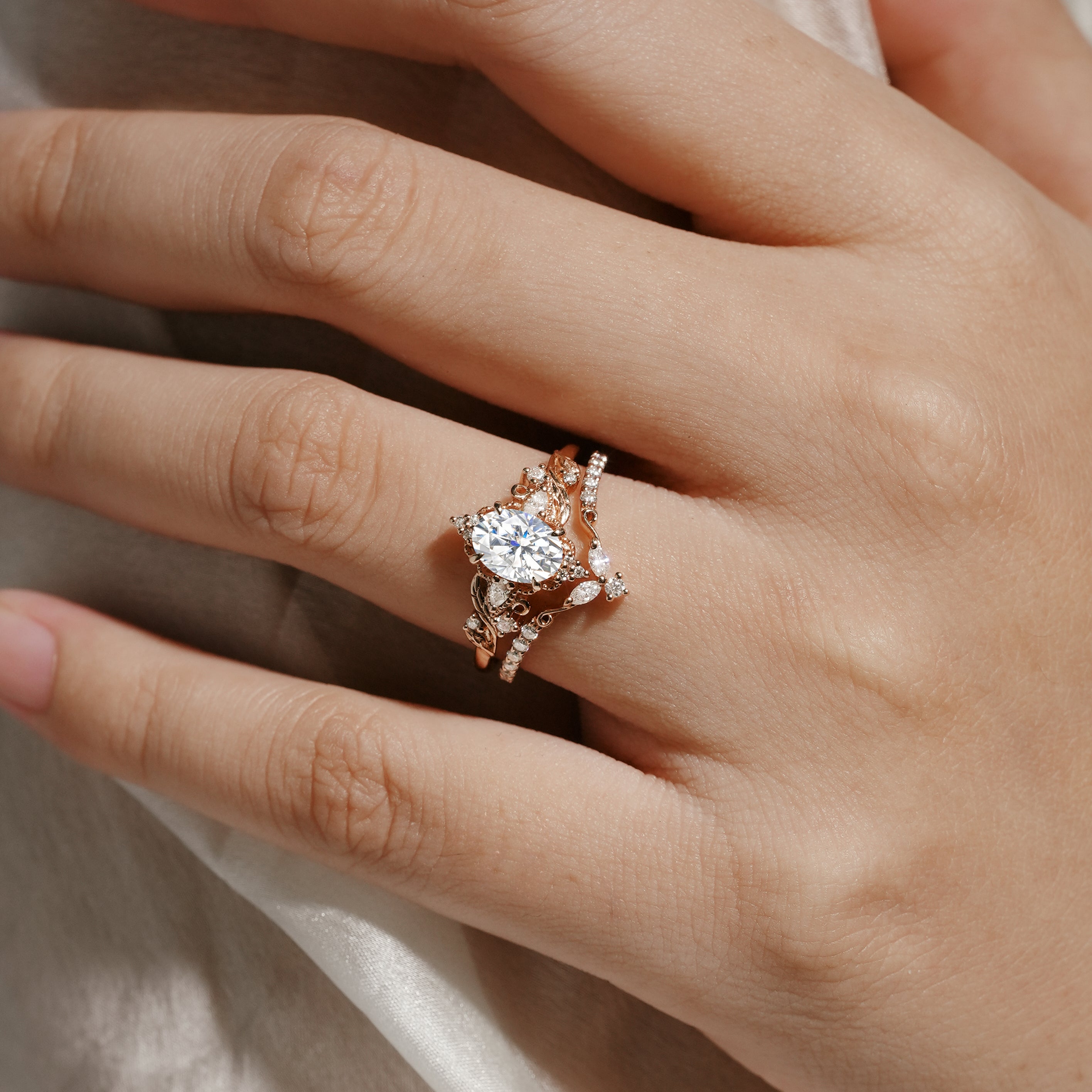 Rose gold leaf-inspired moissanite ring set on hand, bridal jewelry. Includes engagement ring and wedding band.