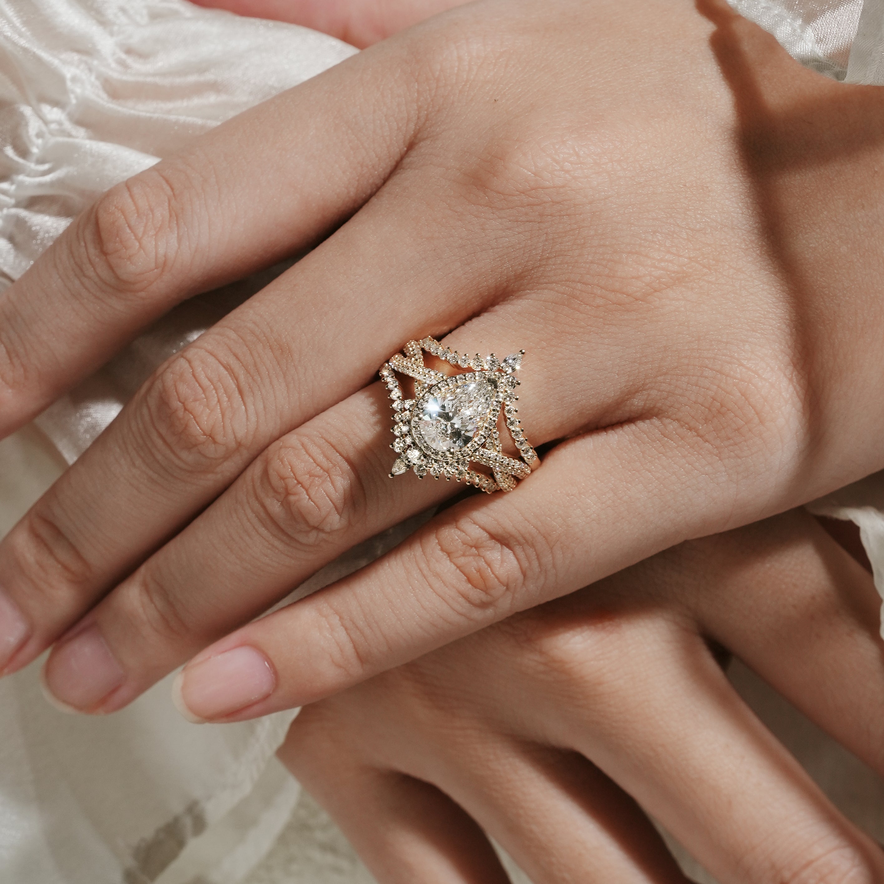 Woman's hand wearing a pear cut halo moissanite engagement ring set