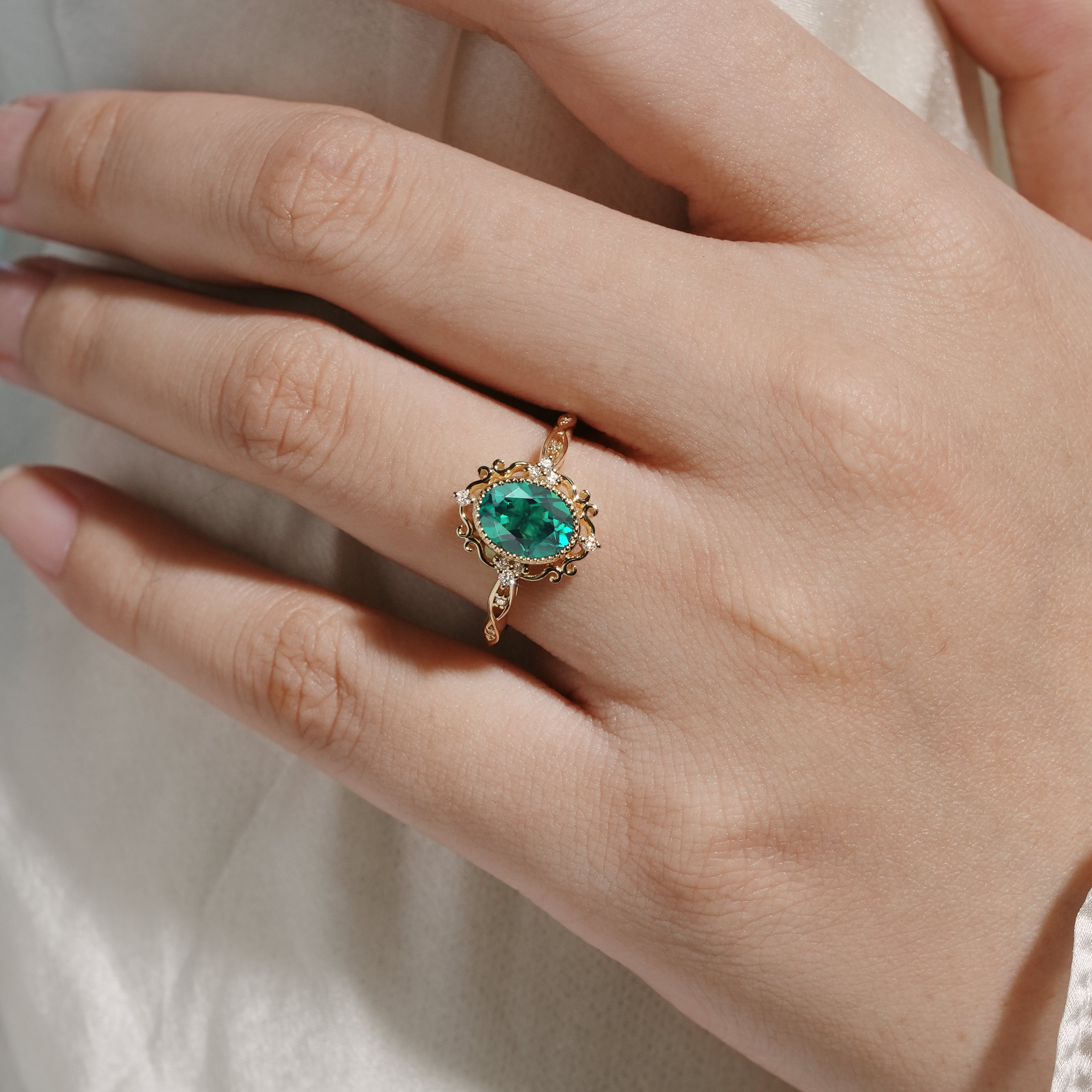 Vintage emerald engagement ring with lab-grown emerald and moissanite accents, gold band.