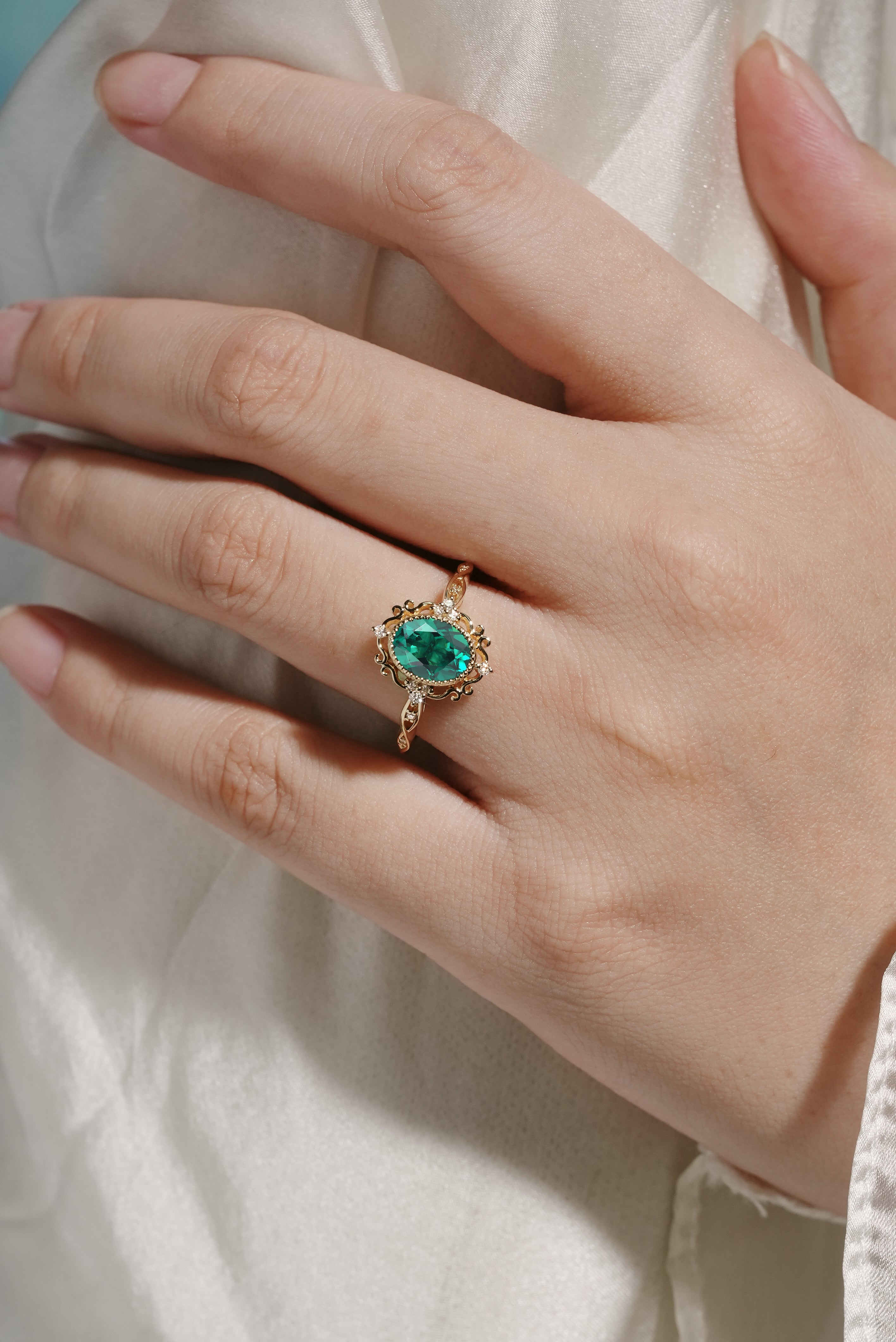 Vintage emerald engagement ring with lab-grown emerald and moissanite accents, gold band.