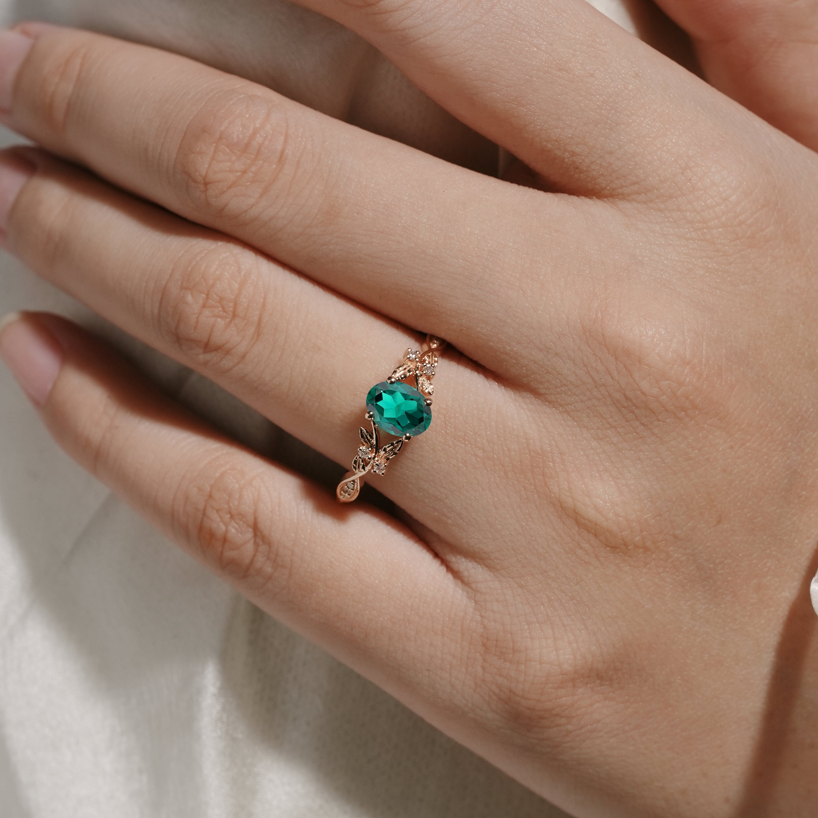 Oval lab-grown emerald engagement ring with leaf design in rose gold. Wedding ring.