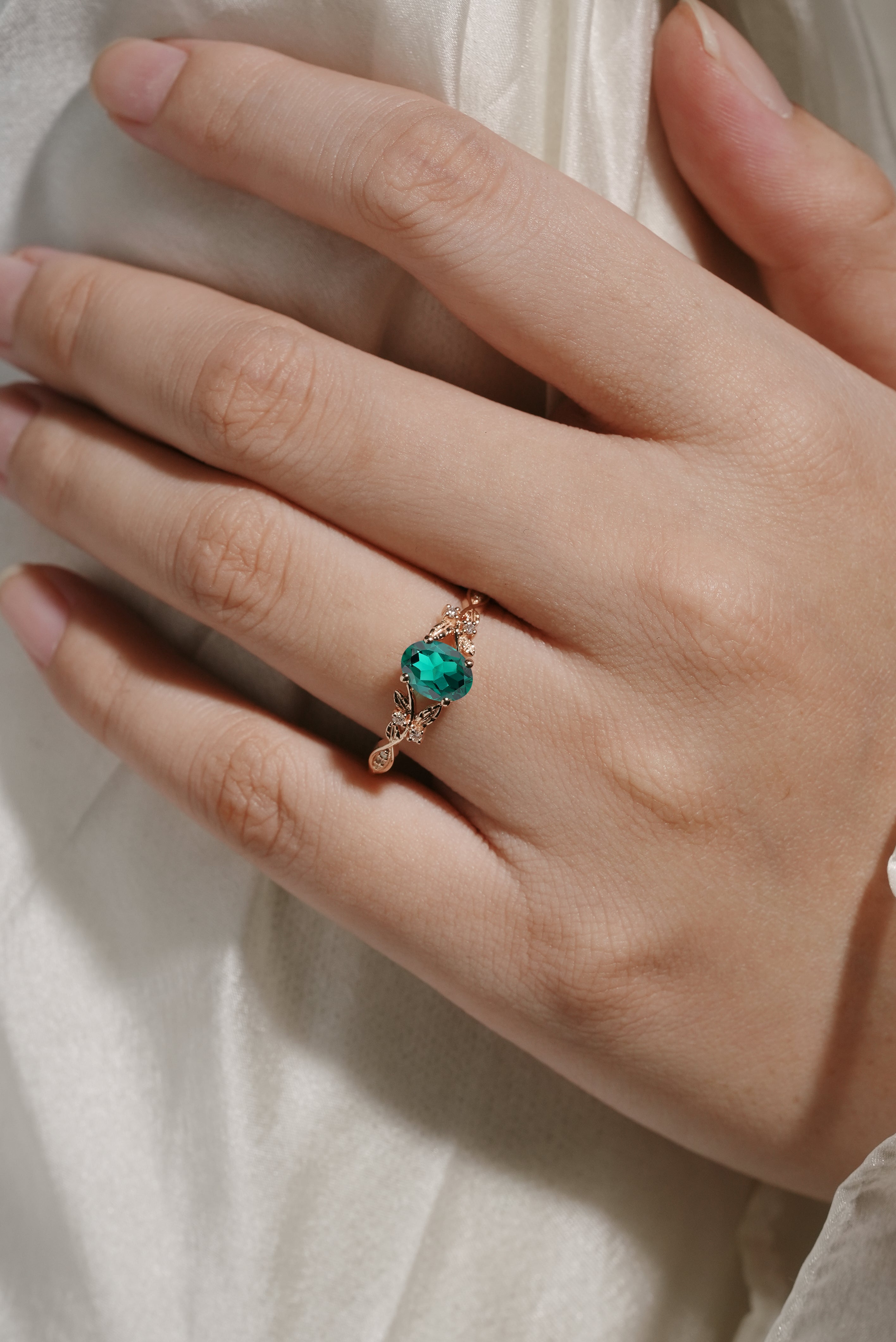 Oval lab-grown emerald engagement ring with leaf design in rose gold. Wedding ring.
