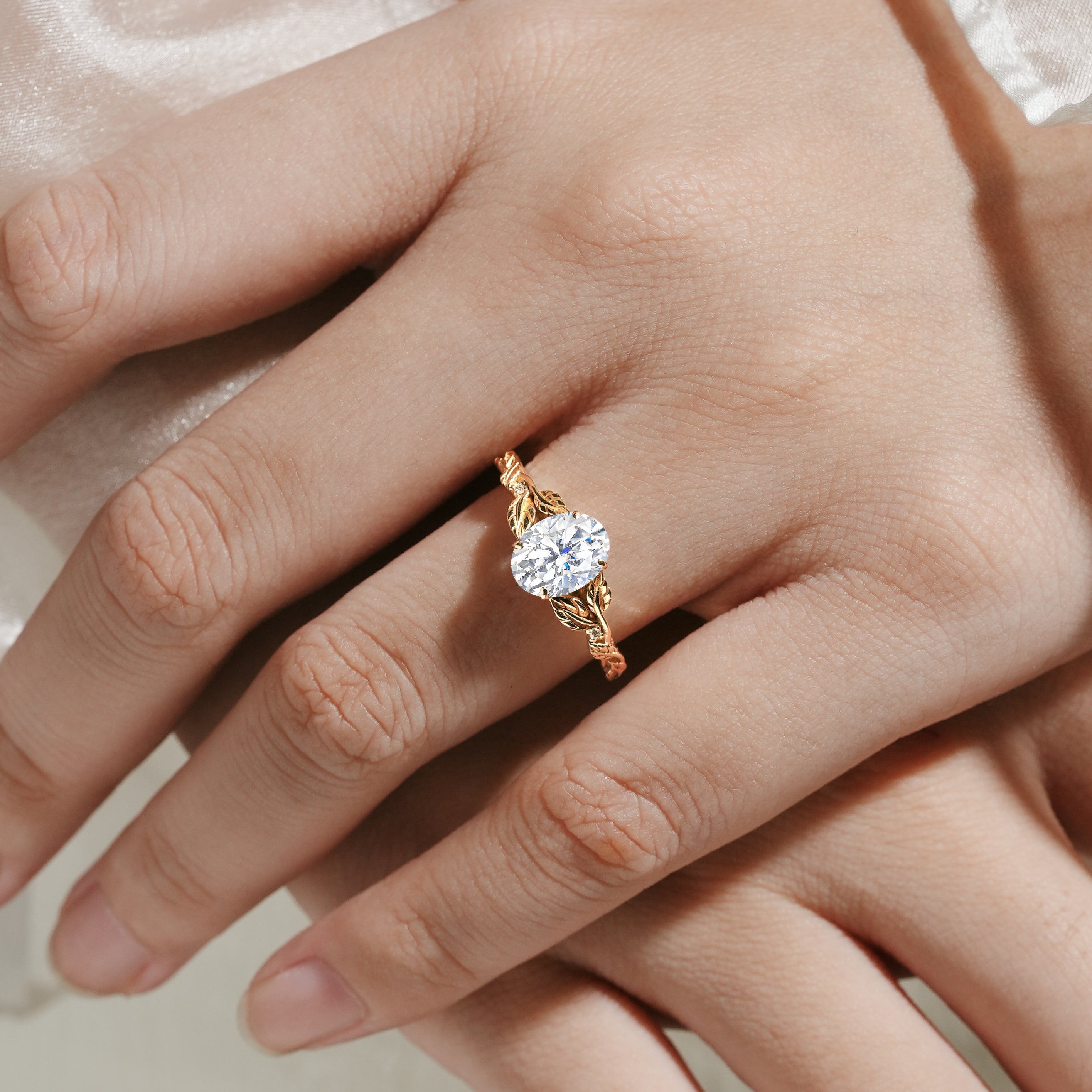 Oval moissanite engagement ring with leaf band, gold. Ideal for bridal, wedding. Featuring a beautiful design on a hand.