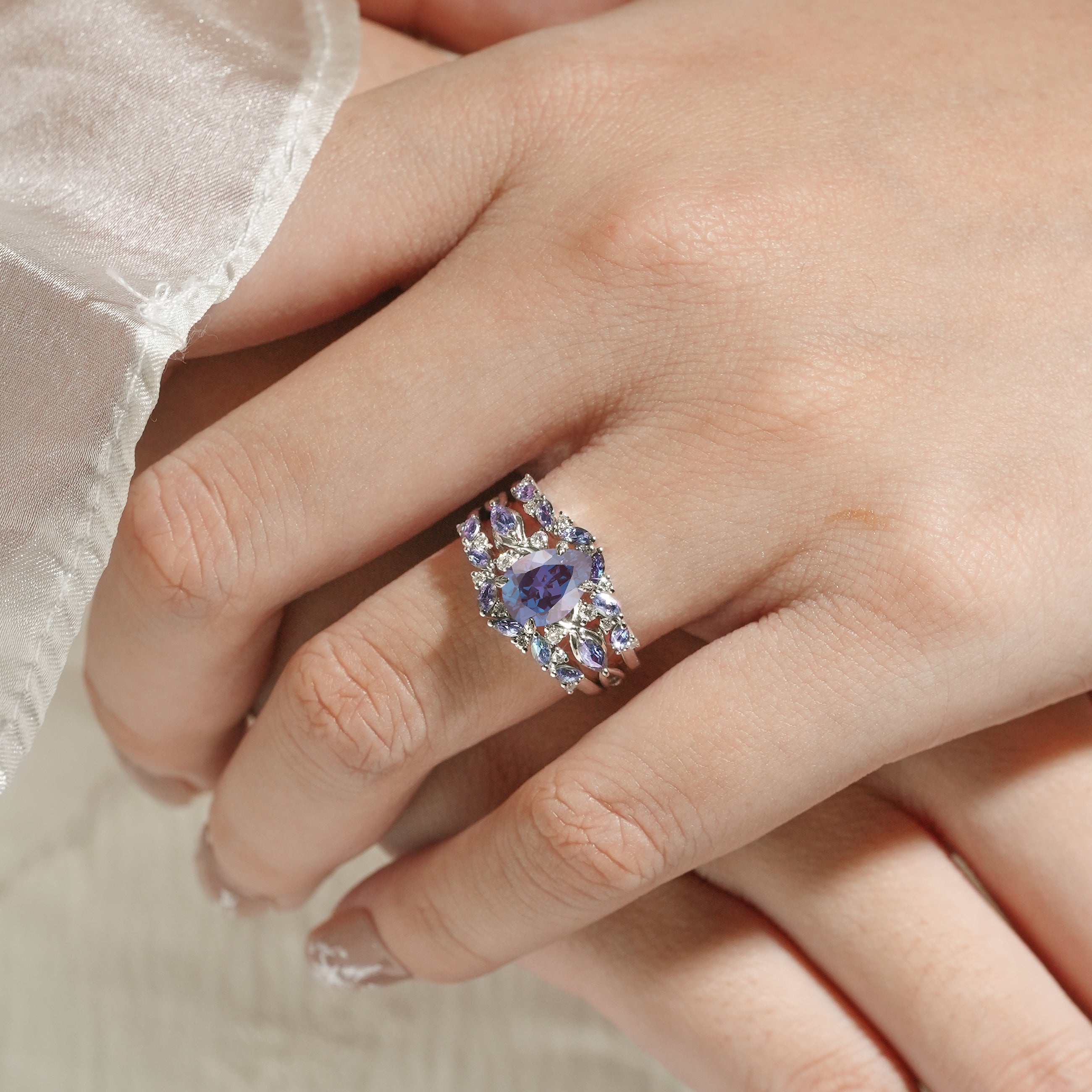 Alexandrite pear cut engagement ring with enhancer wedding band on finger