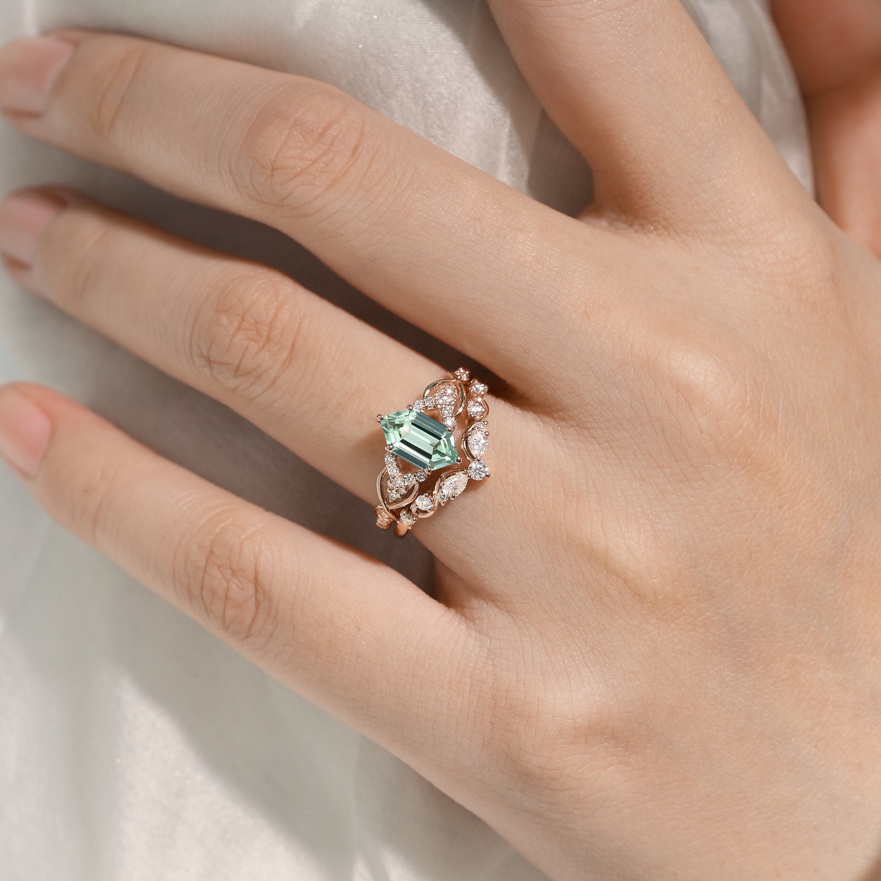 Hand wearing a green sapphire engagement ring and wedding band set