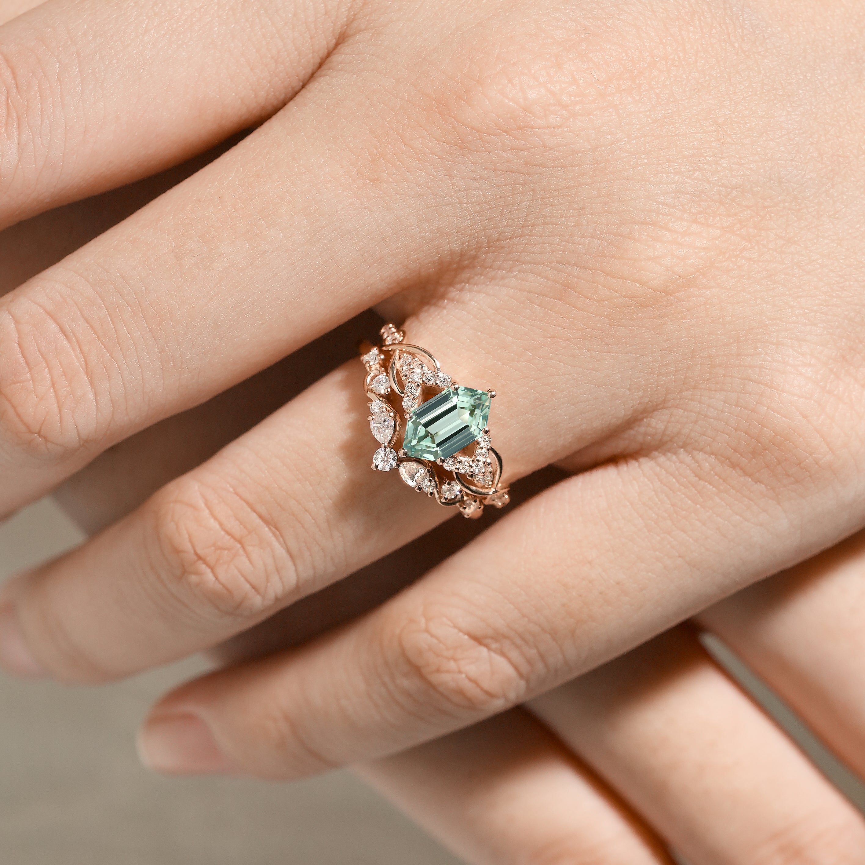 Close-up of a hand wearing a green sapphire and moissanite bridal set ring, nature-inspired