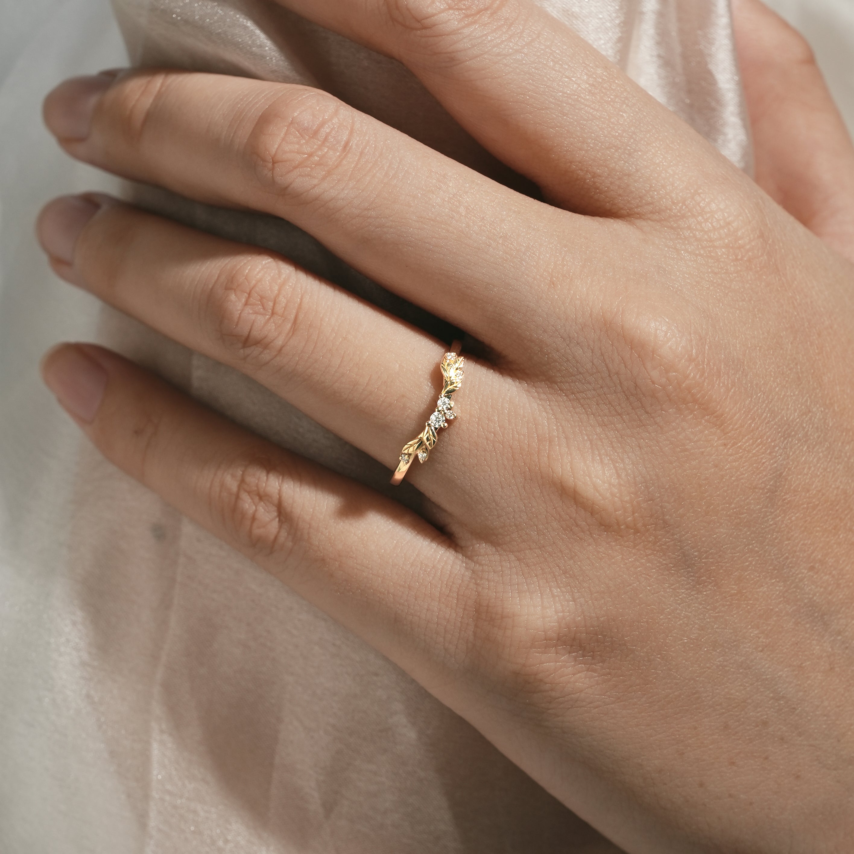 Gold wedding band with leaf pattern and moissanite stones, nature-inspired design.