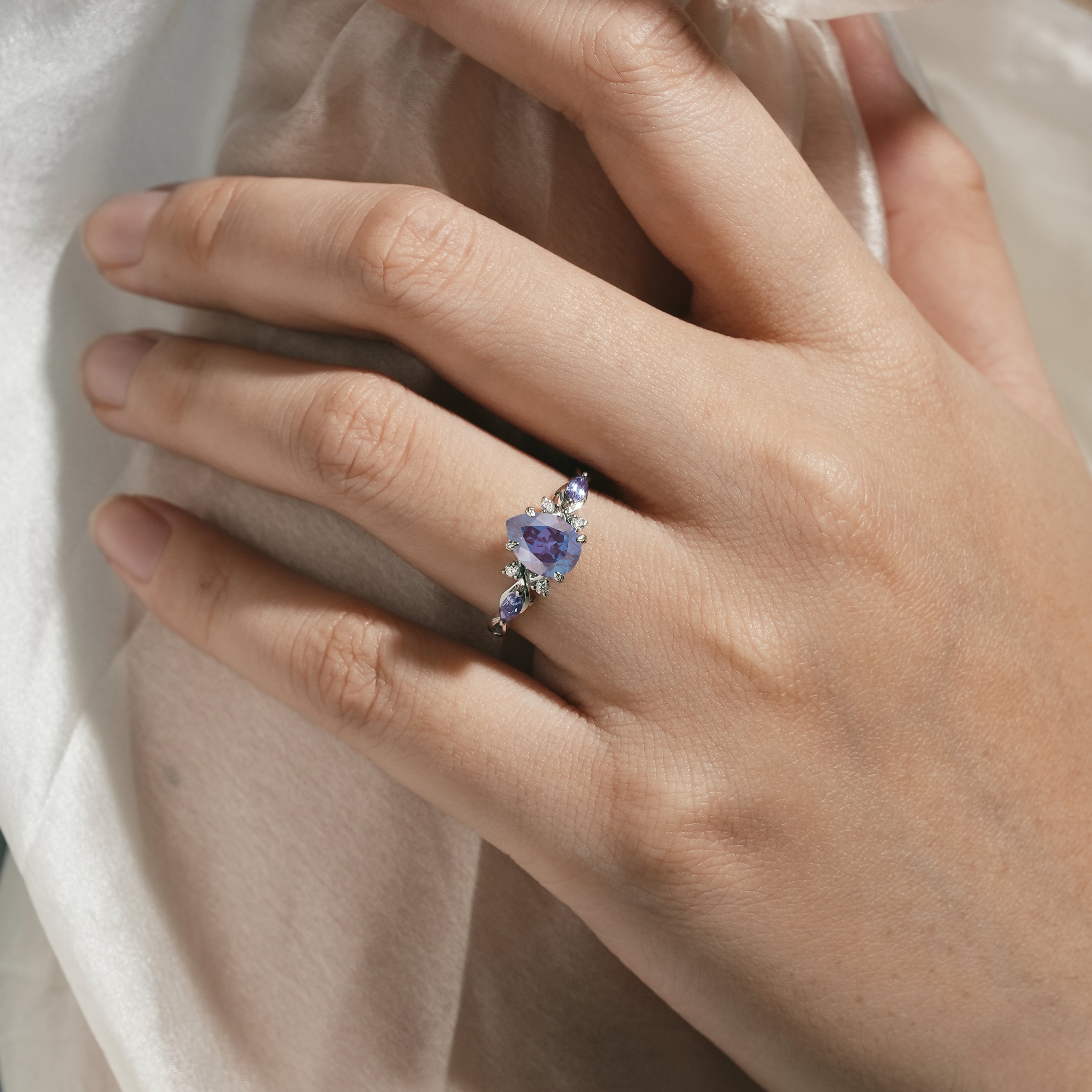 Elegant pear-cut alexandrite engagement ring on hand, moissanite accents, Lahela Jewelry.