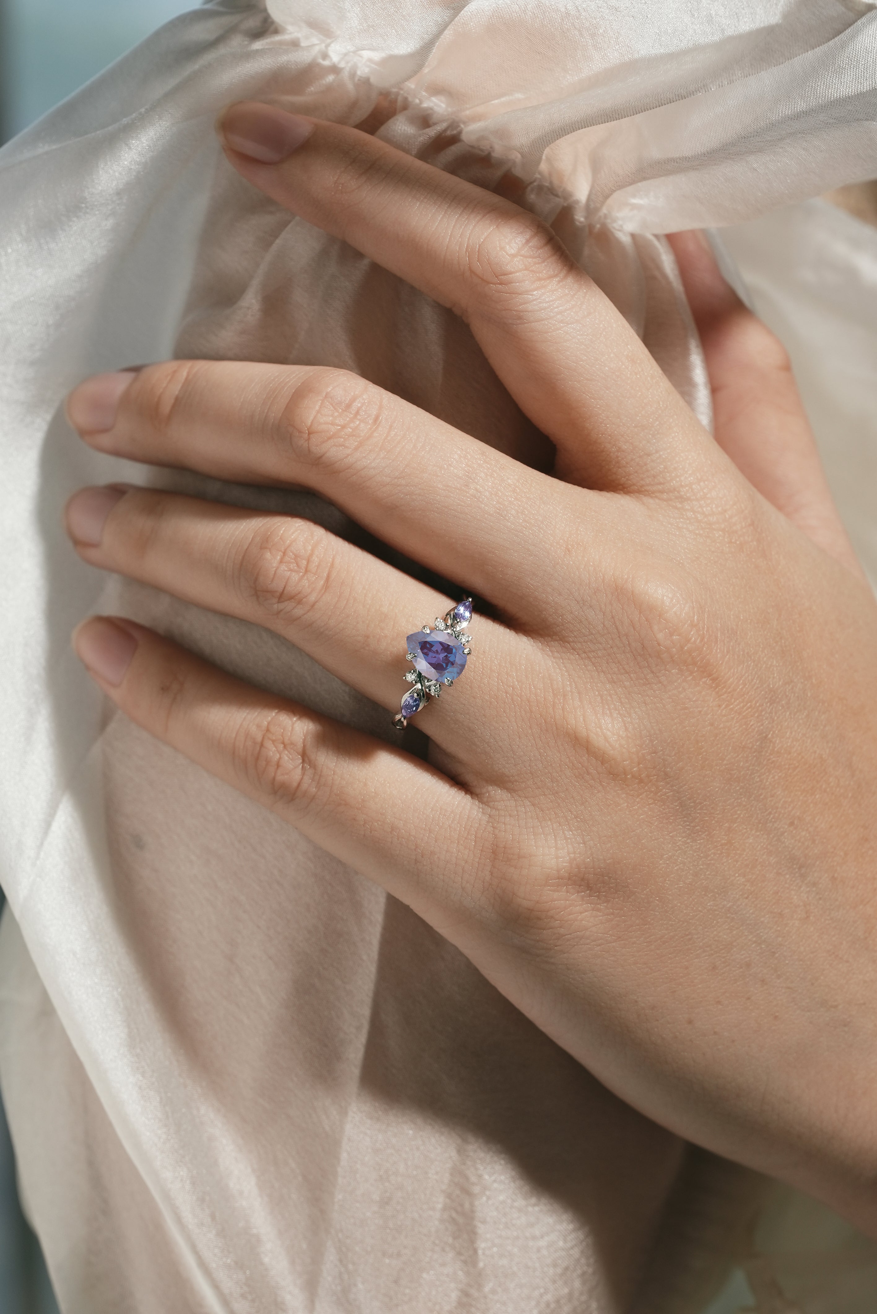Elegant pear-cut alexandrite engagement ring on hand, moissanite accents, Lahela Jewelry.