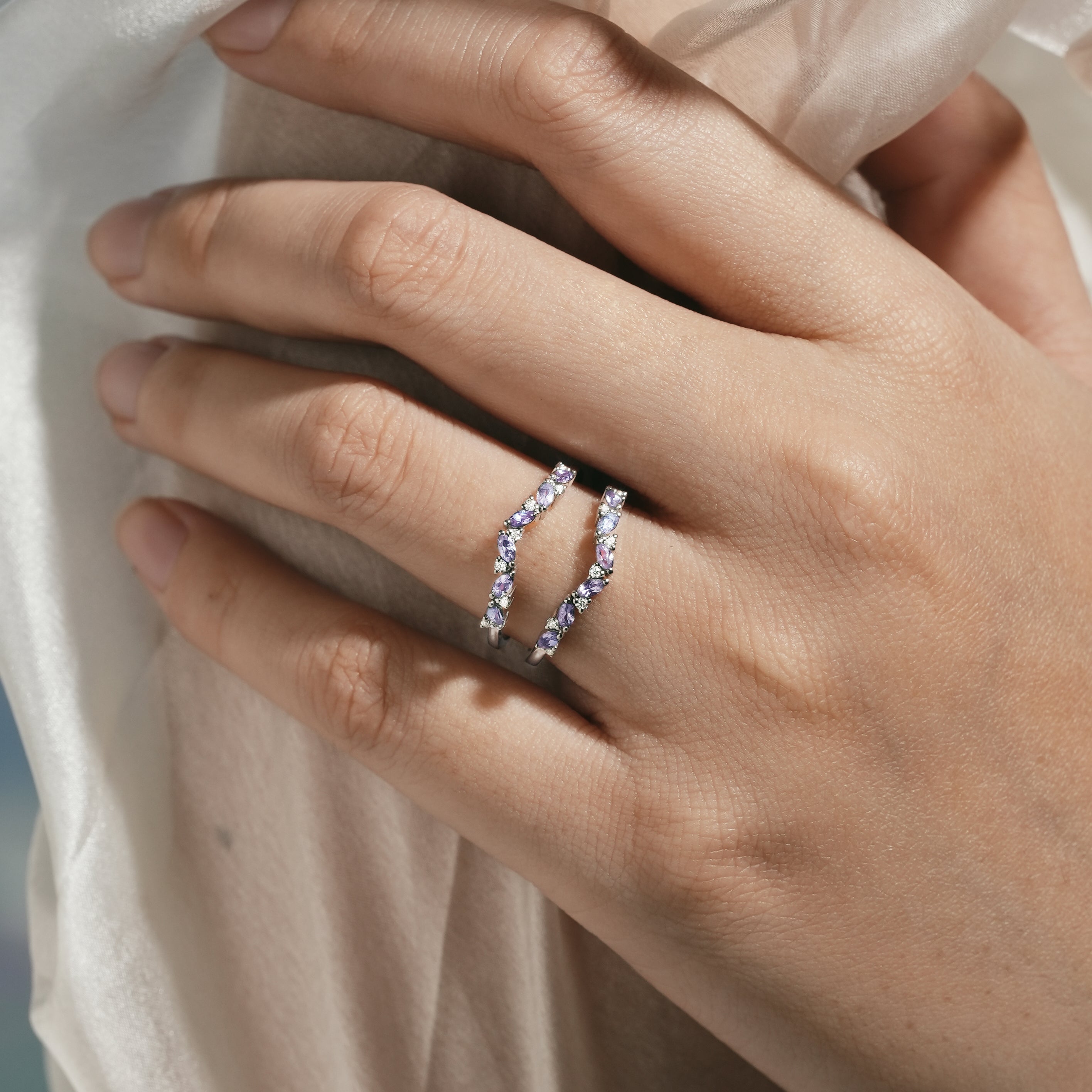Close-up of an Alexandrite enhancer wedding band on a hand, showcasing moissanite stones, bridal set ring.