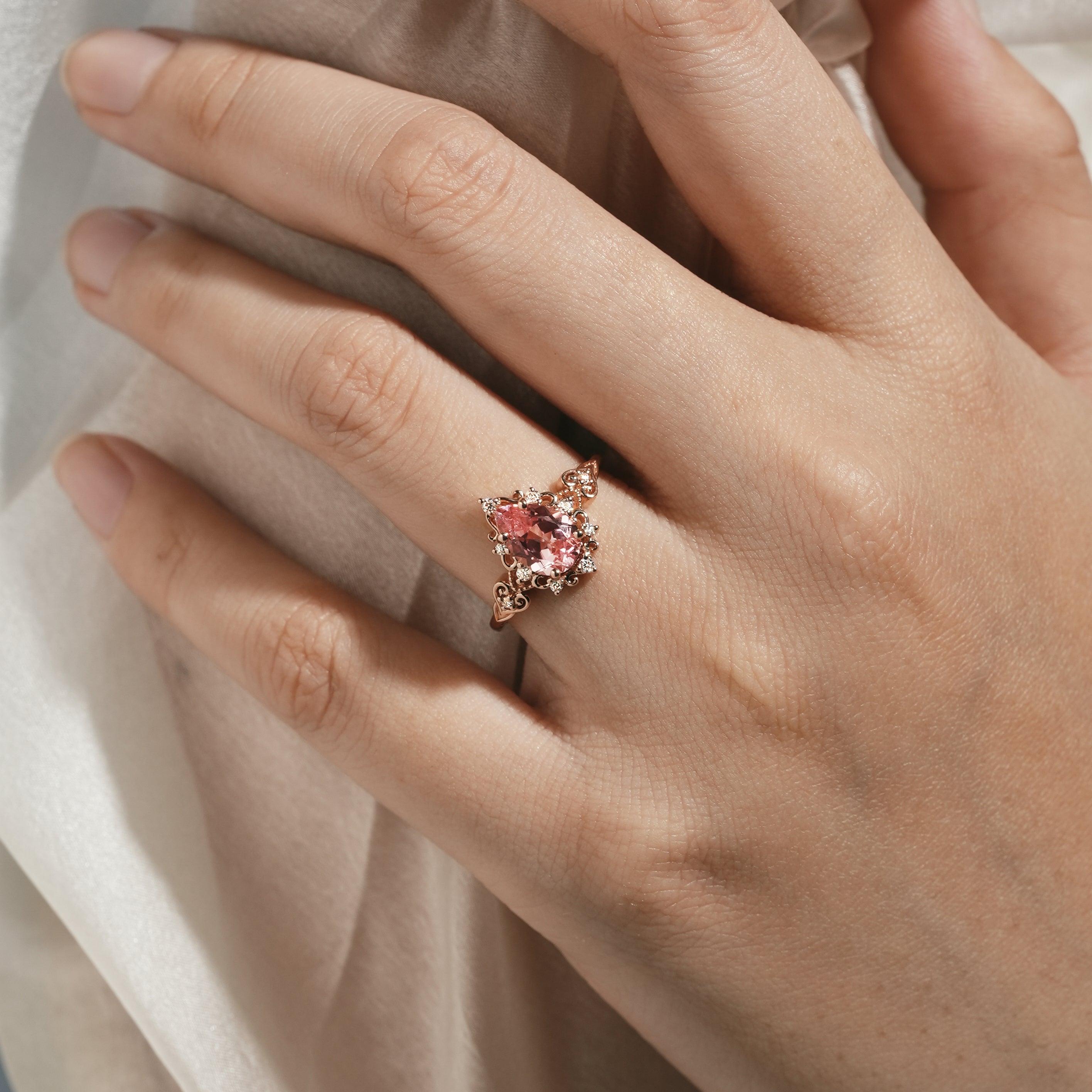 Vintage Padparadscha sapphire engagement ring on a hand, rose gold