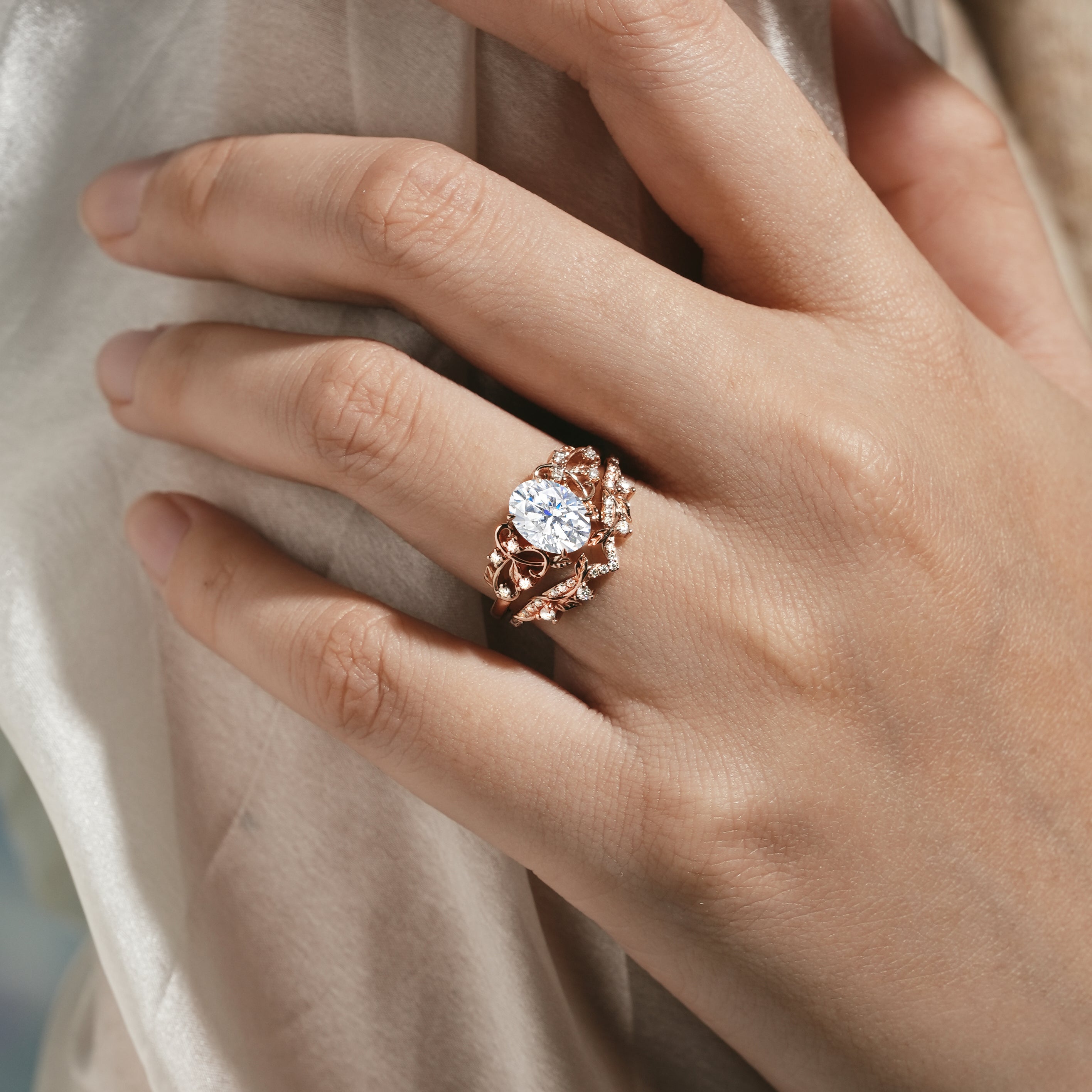 Rose gold leaf engagement ring set with oval moissanite on a hand