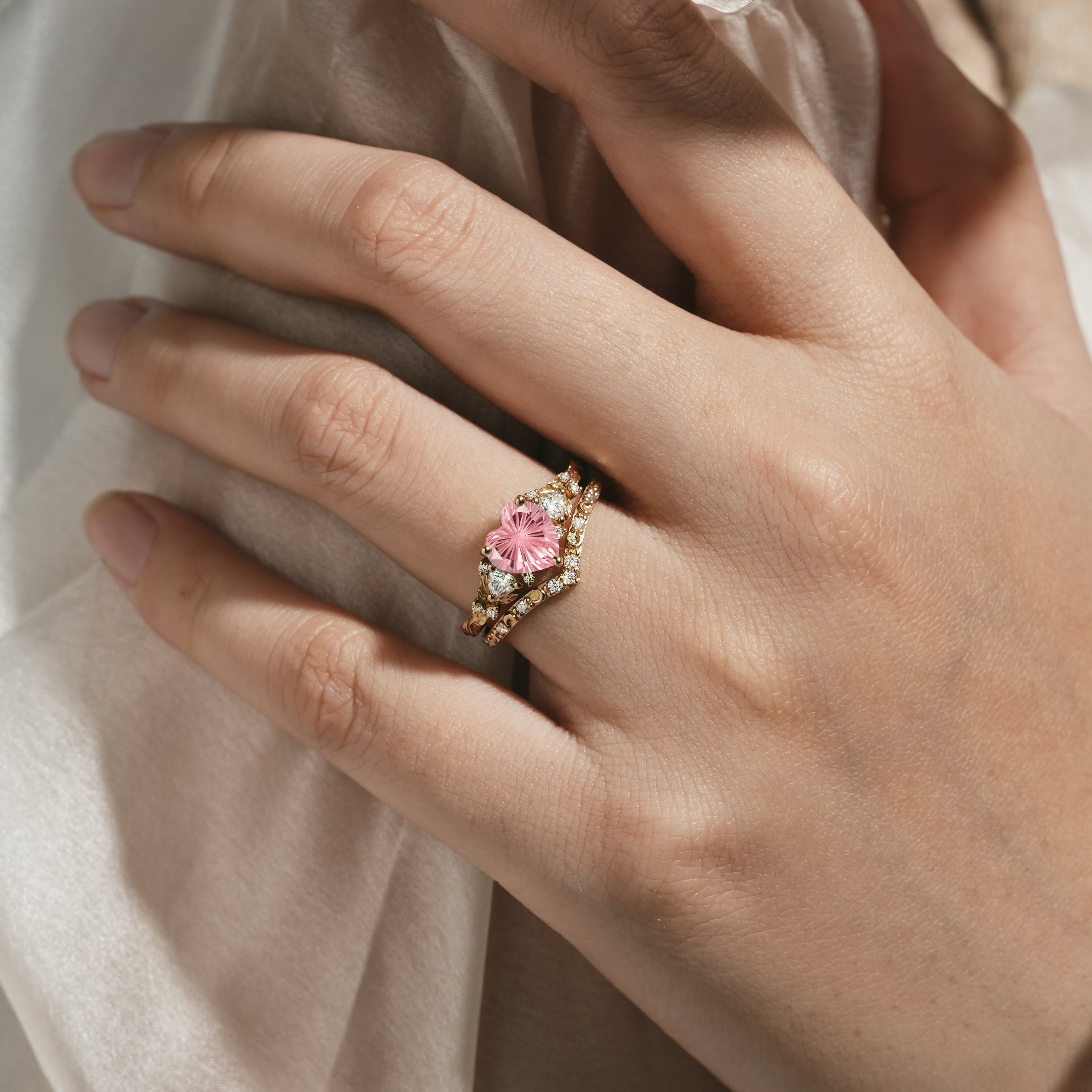 Heart-cut Padparadscha engagement ring set on a hand
