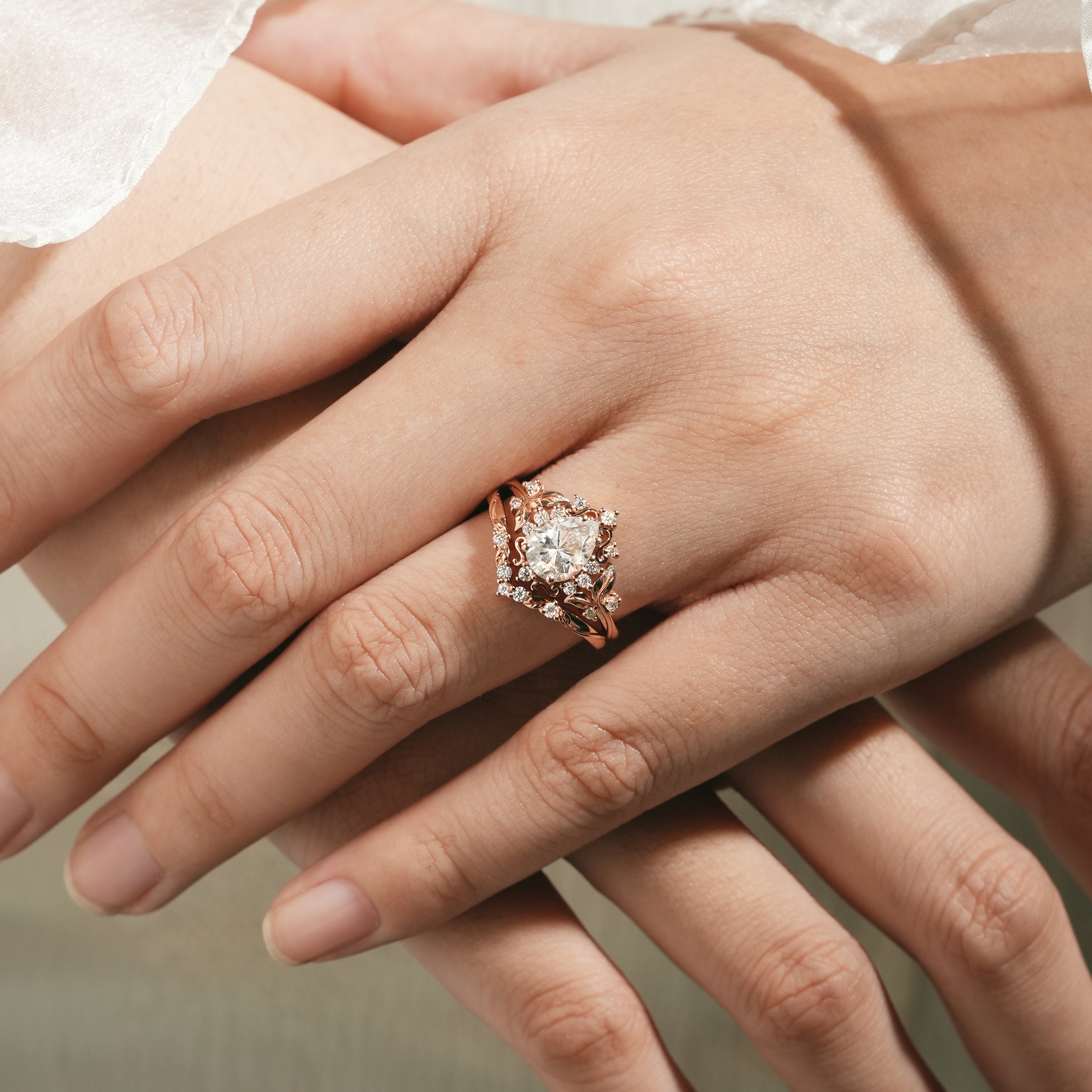 Woman's hand wearing leaf-inspired engagement ring set, rose gold