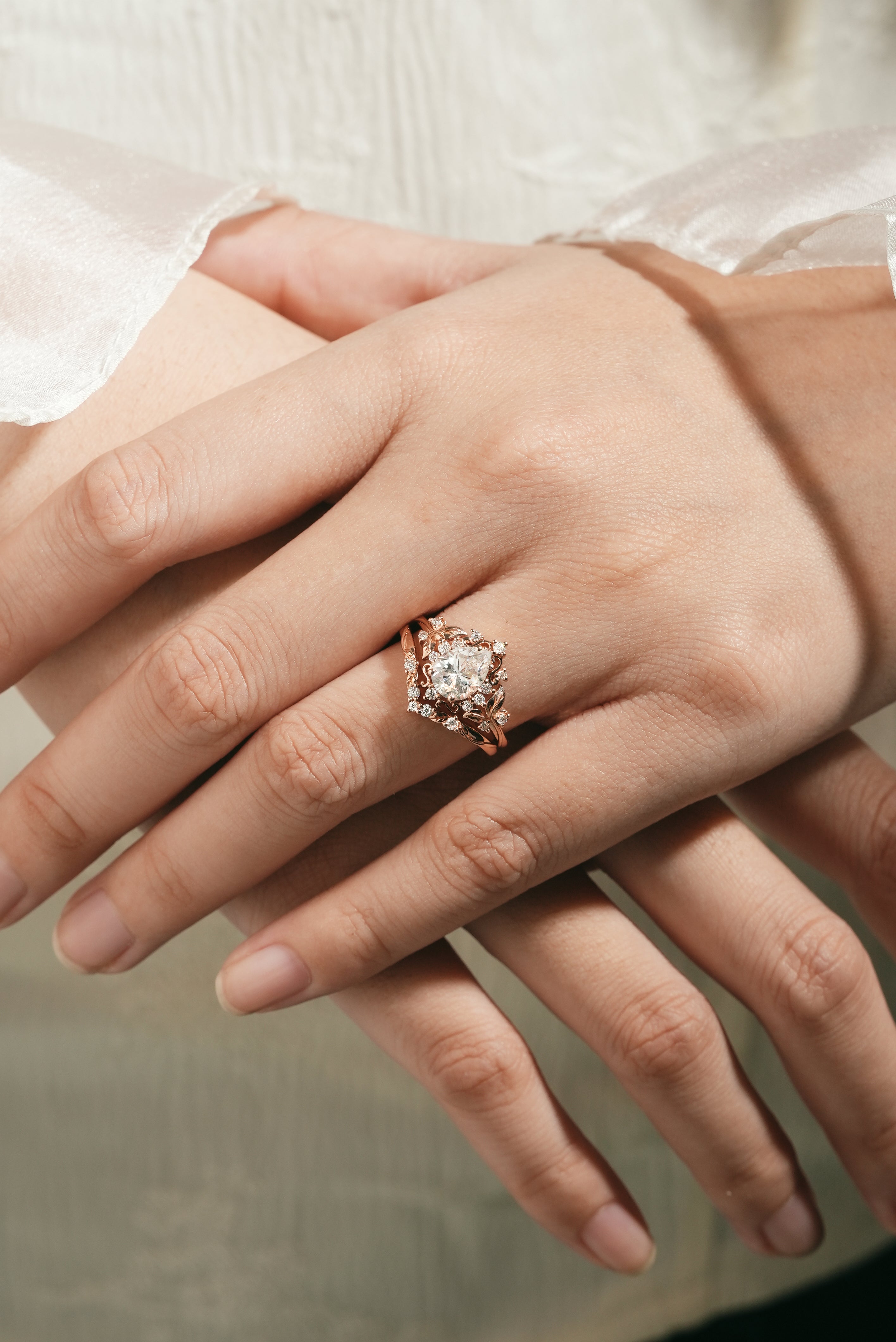 Woman's hand wearing leaf-inspired engagement ring set, rose gold