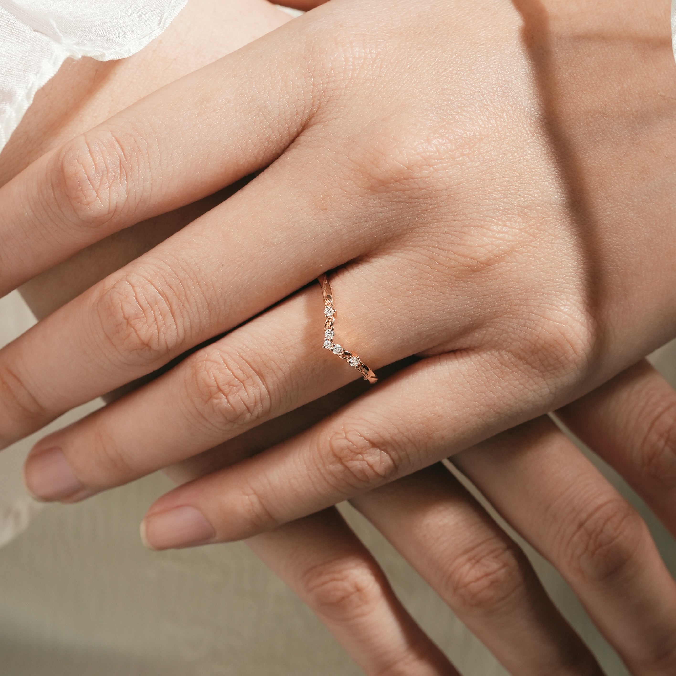 Woman's hand wearing a V-shaped moissanite wedding band