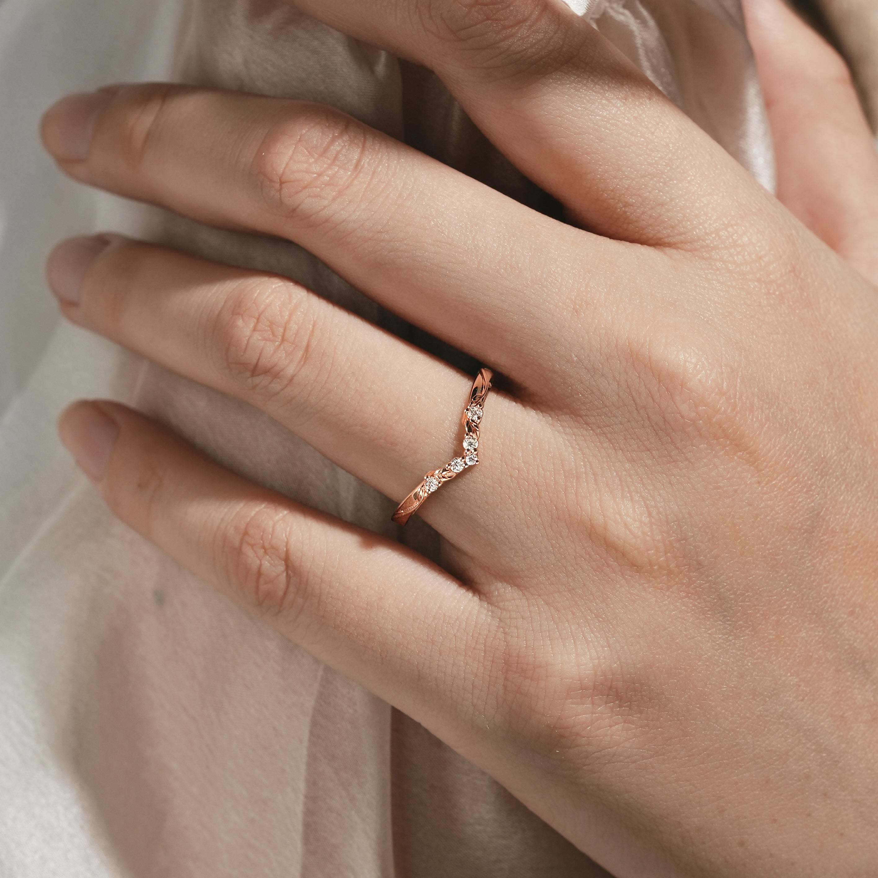 Rose gold V-shaped leaf moissanite wedding band on hand