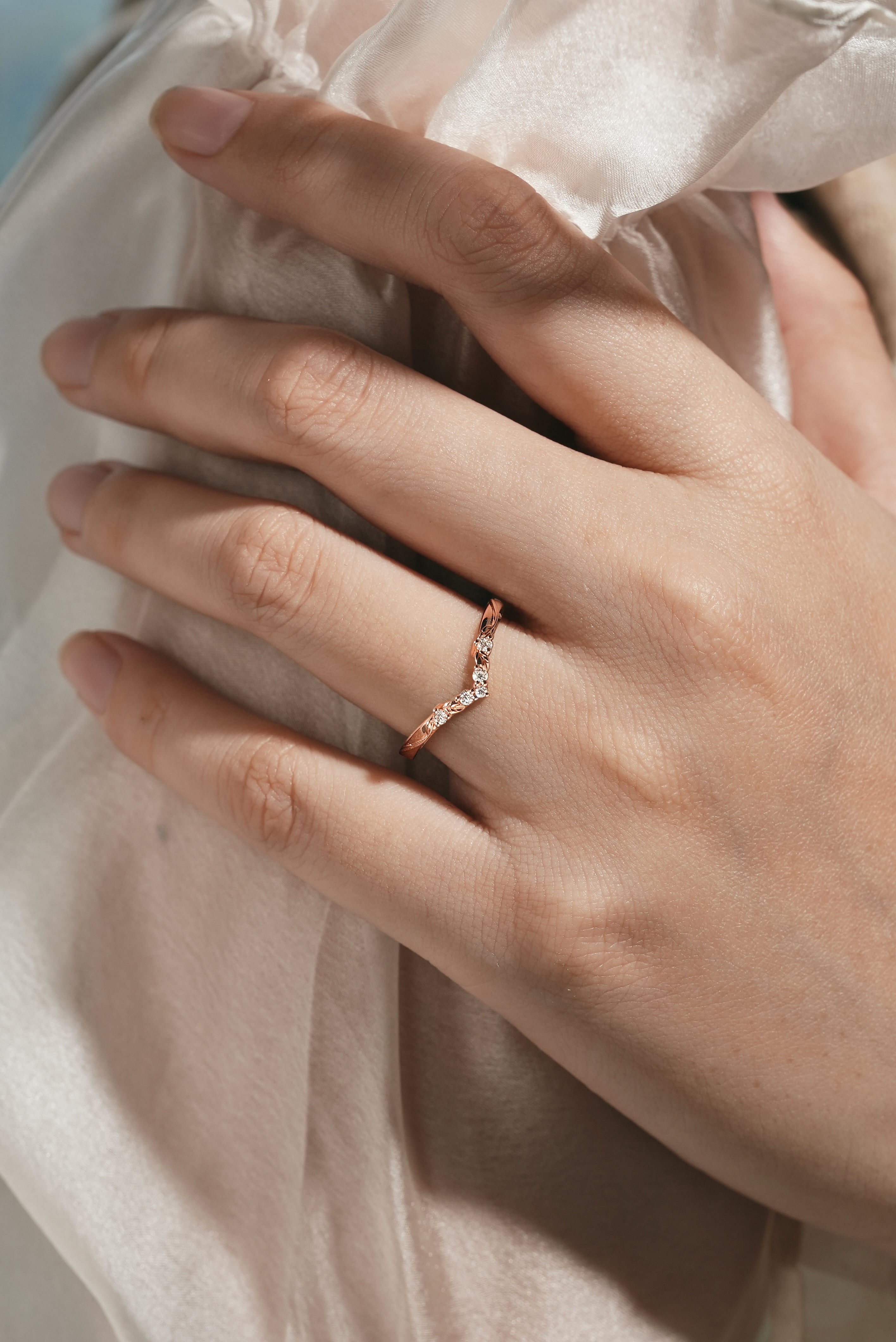 Rose gold V-shaped leaf moissanite wedding band on hand