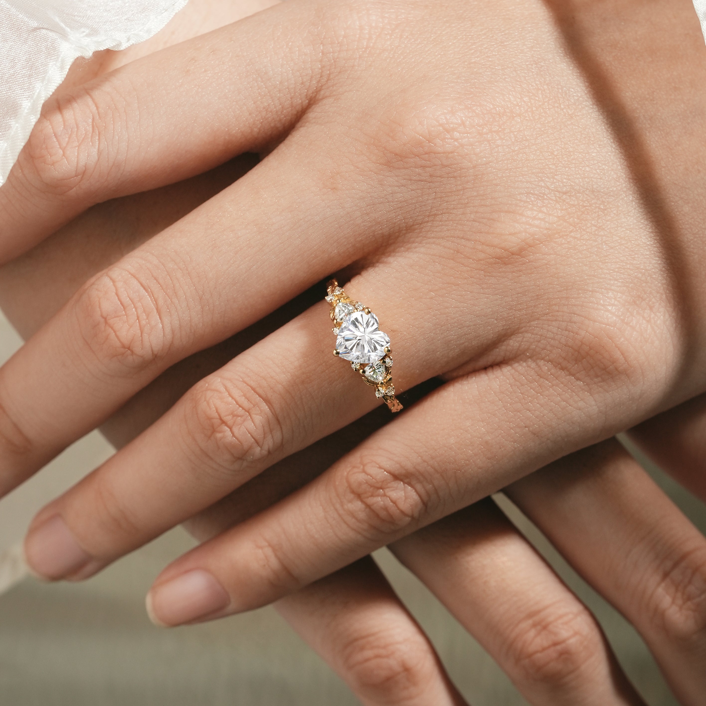 Elegant heart-cut moissanite ring with leaf accents on a woman's hand.