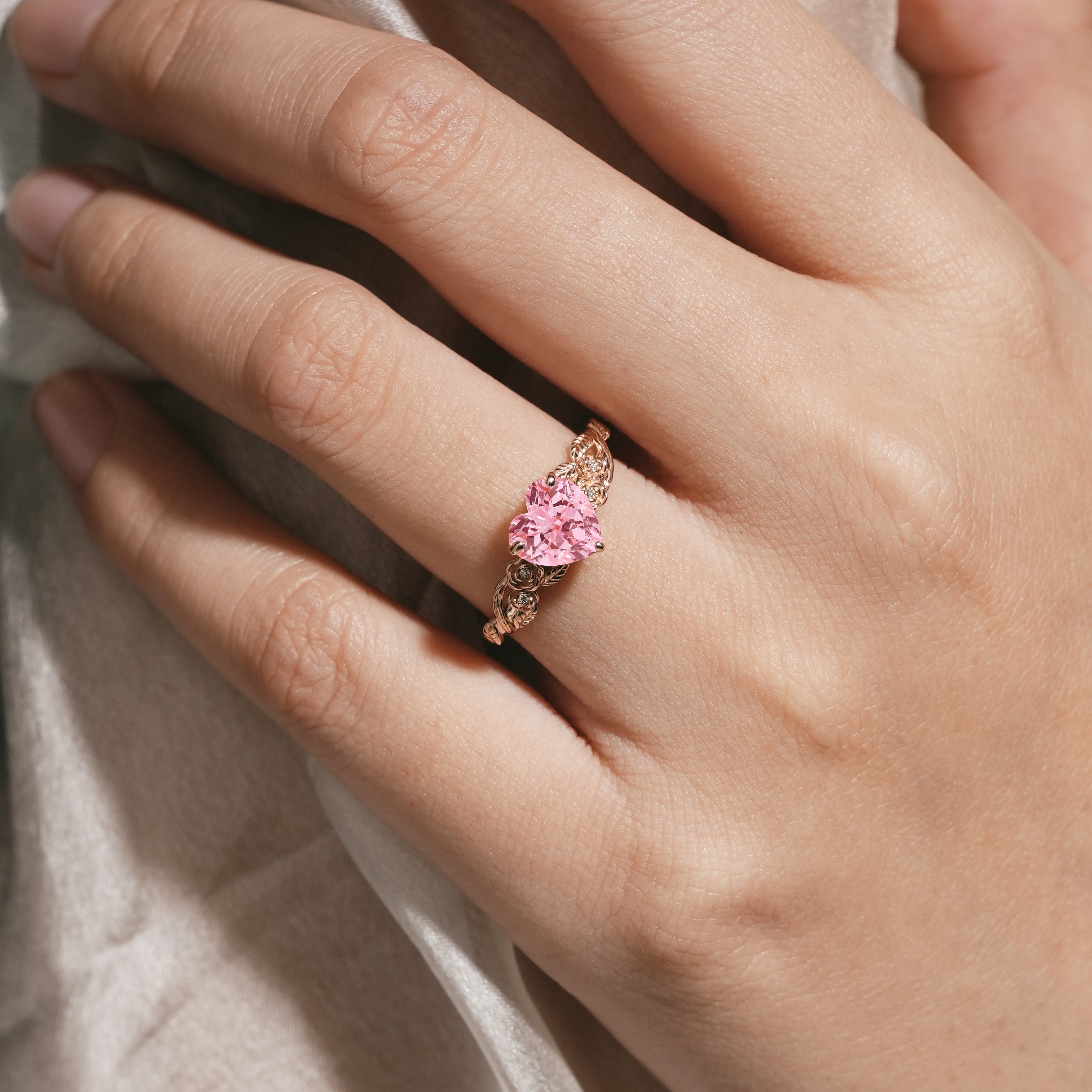 Woman's hand wearing heart-cut Padparadscha sapphire ring