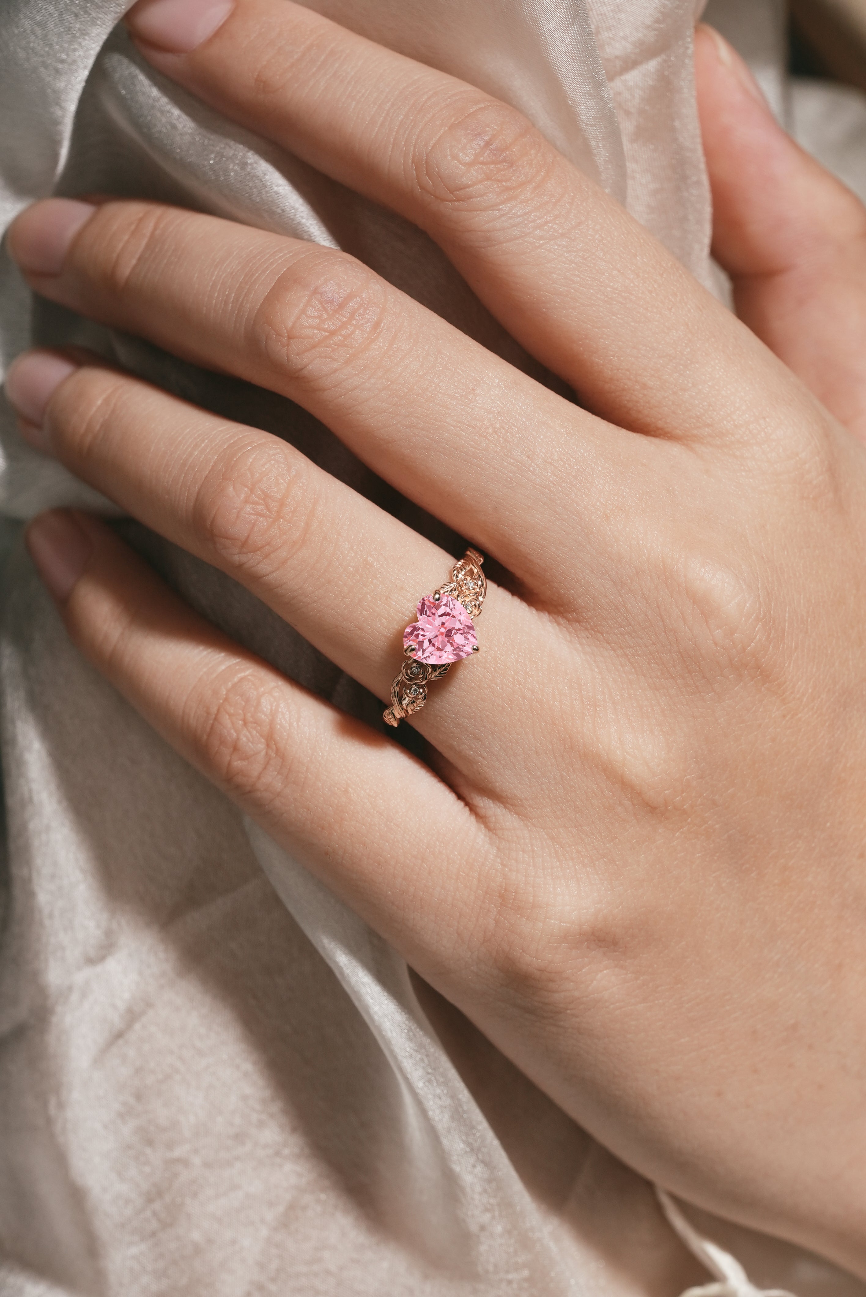 Woman's hand wearing heart-cut Padparadscha sapphire ring