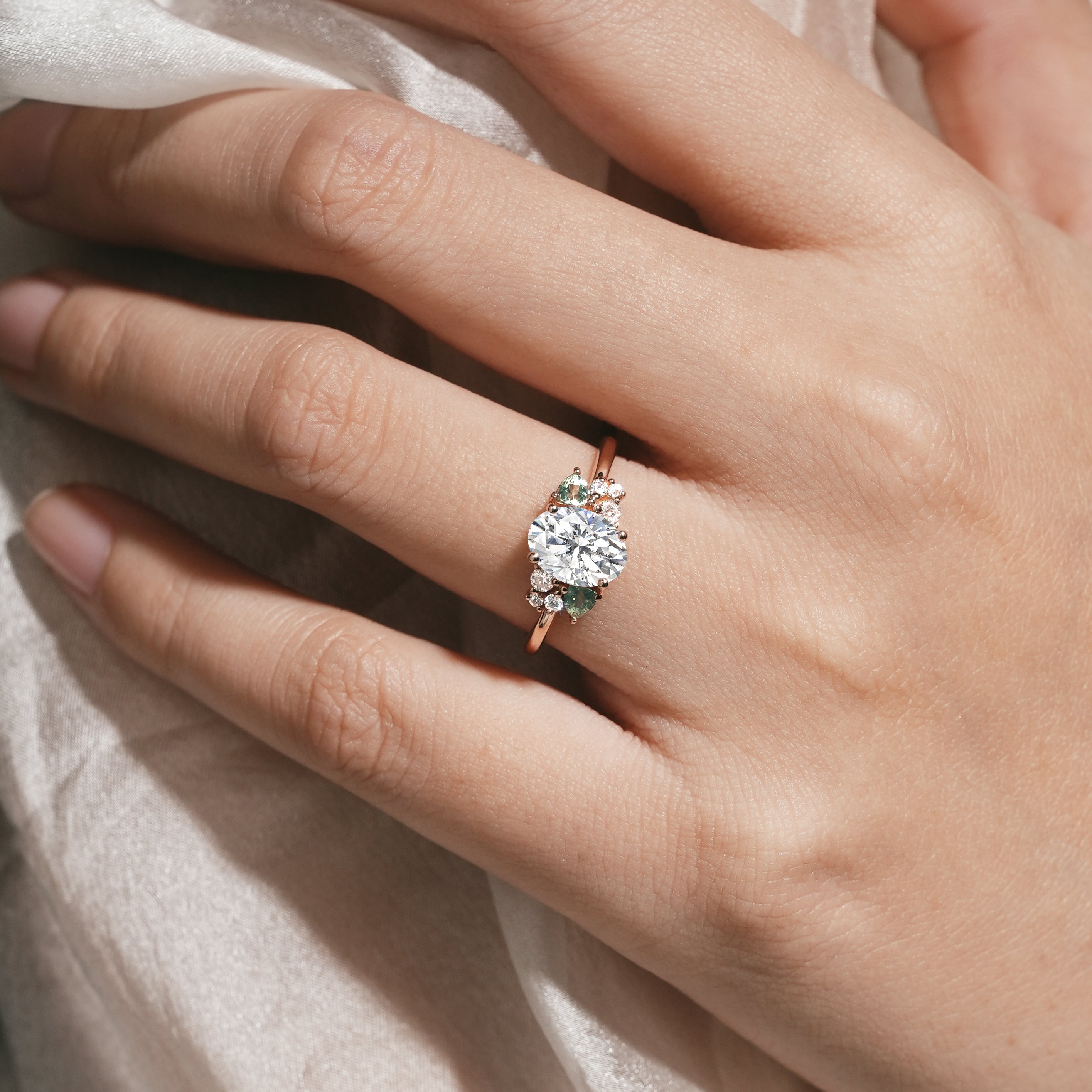 Rose gold oval moissanite ring with spinel cluster on hand