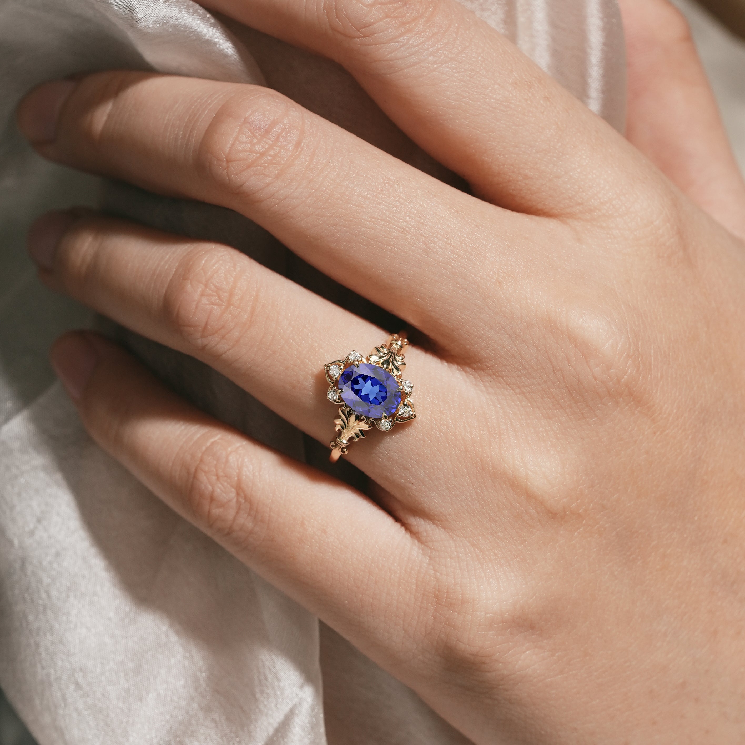 Woman's hand wearing oval royal blue sapphire engagement ring