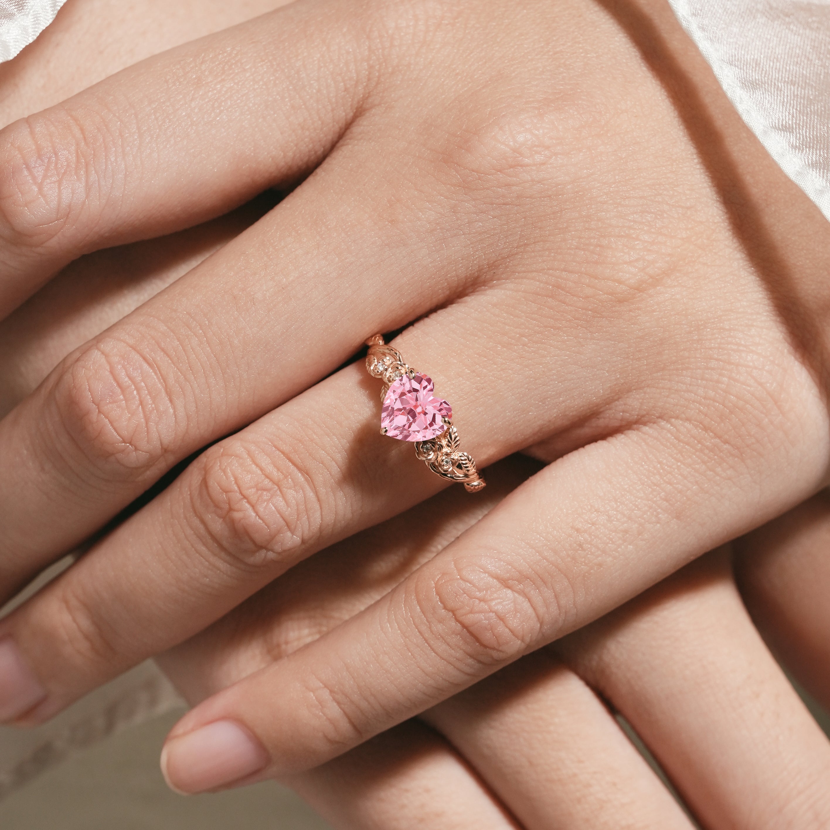 Heart-cut Padparadscha sapphire engagement ring on hand