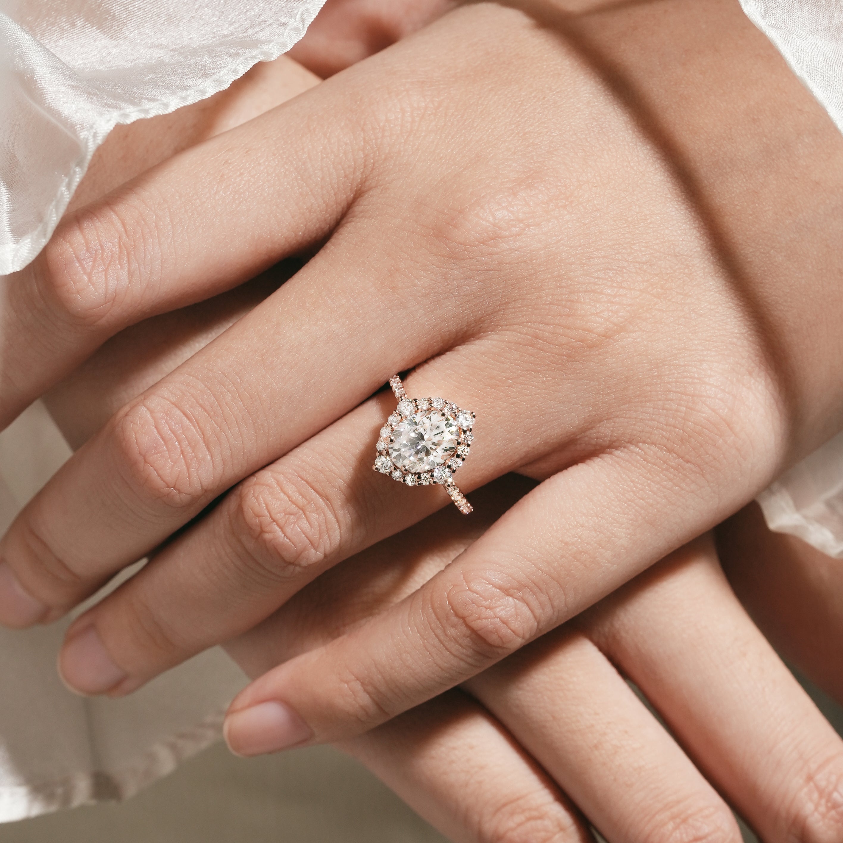 Woman's hand wearing oval cut moissanite halo engagement ring