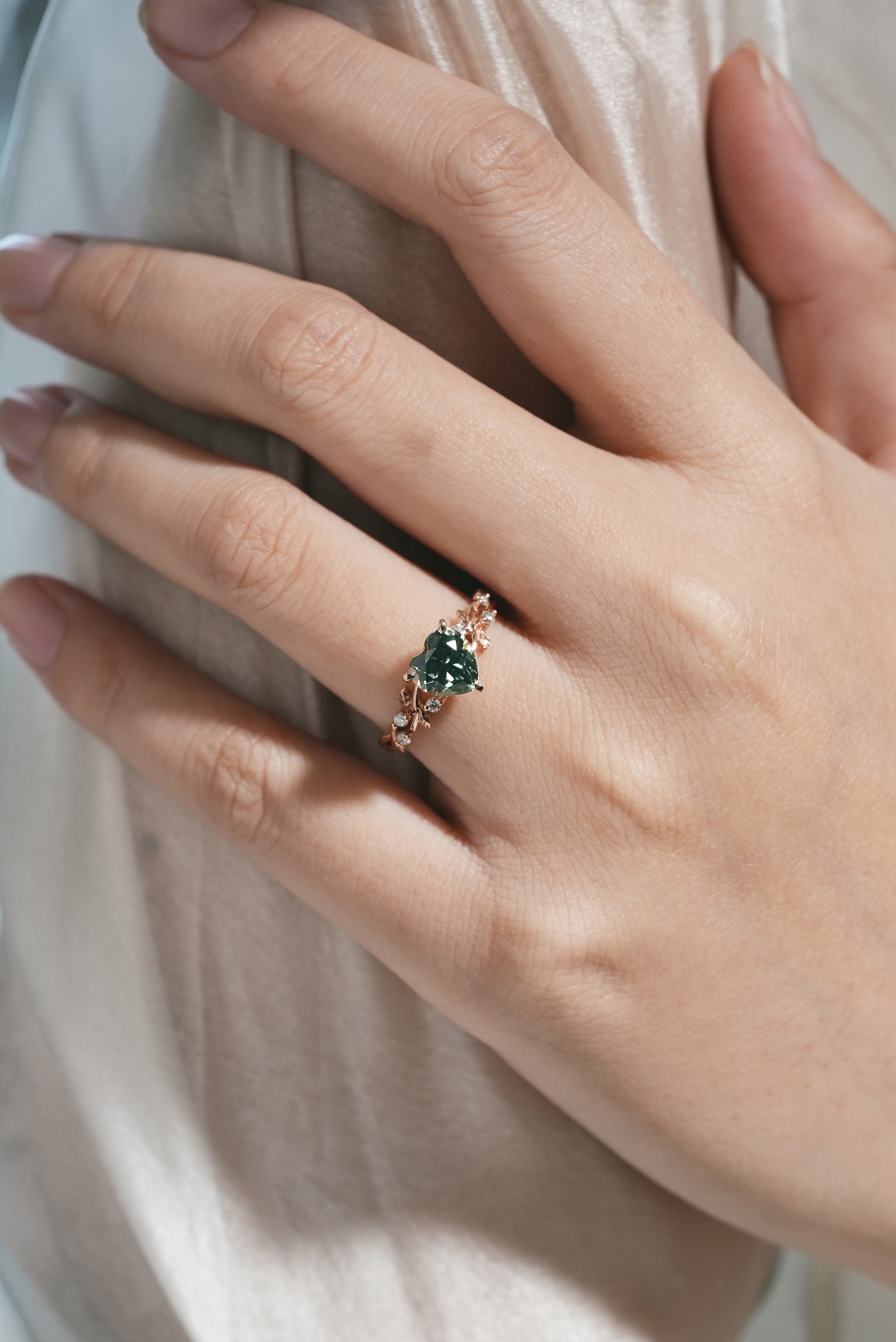 Woman's hand wearing green sapphire leaf engagement ring