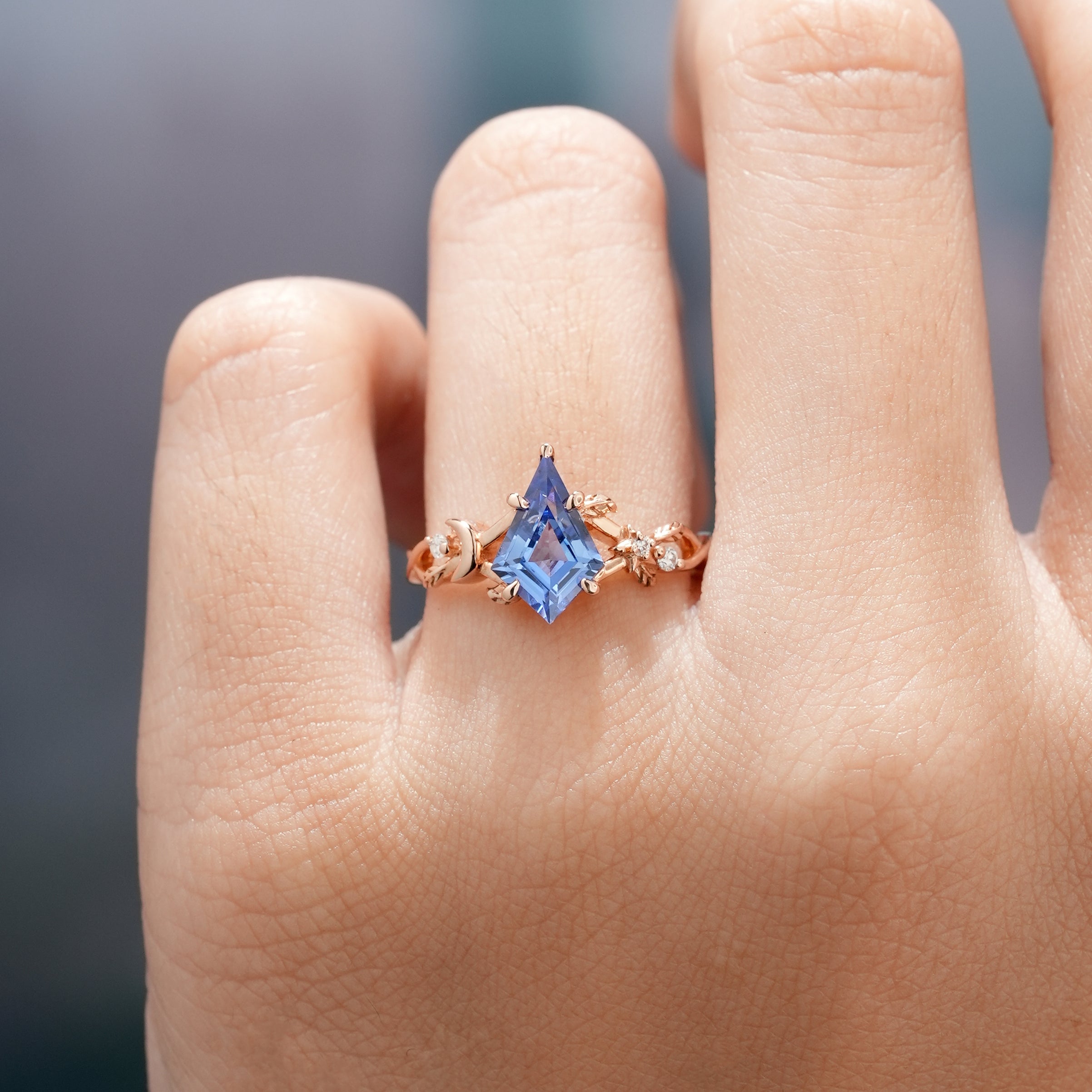 Rose gold kite cut sapphire engagement ring on a hand