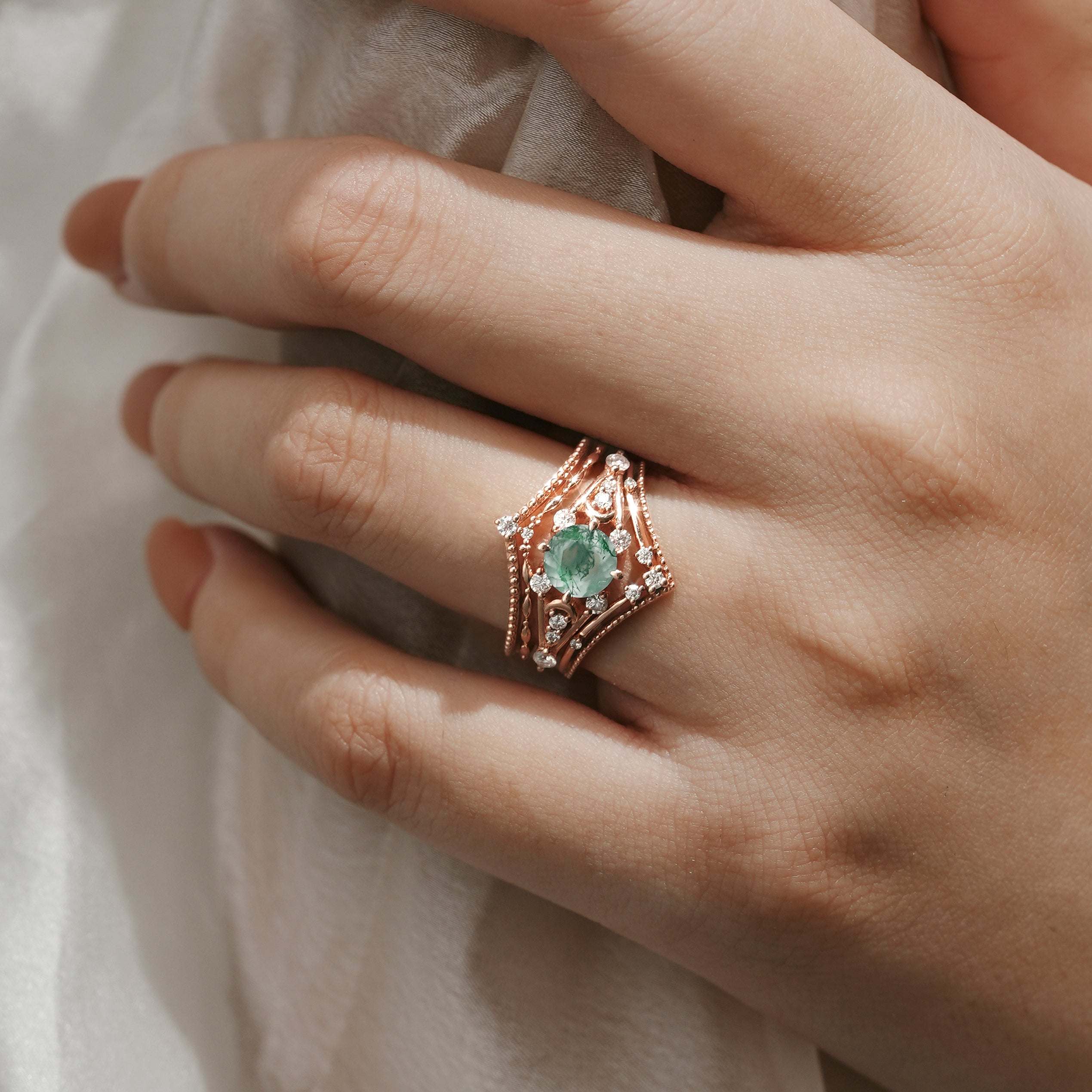 Rose gold moss agate engagement ring set. Moissanite accents, vintage bridal set, wedding band. Hand in focus.