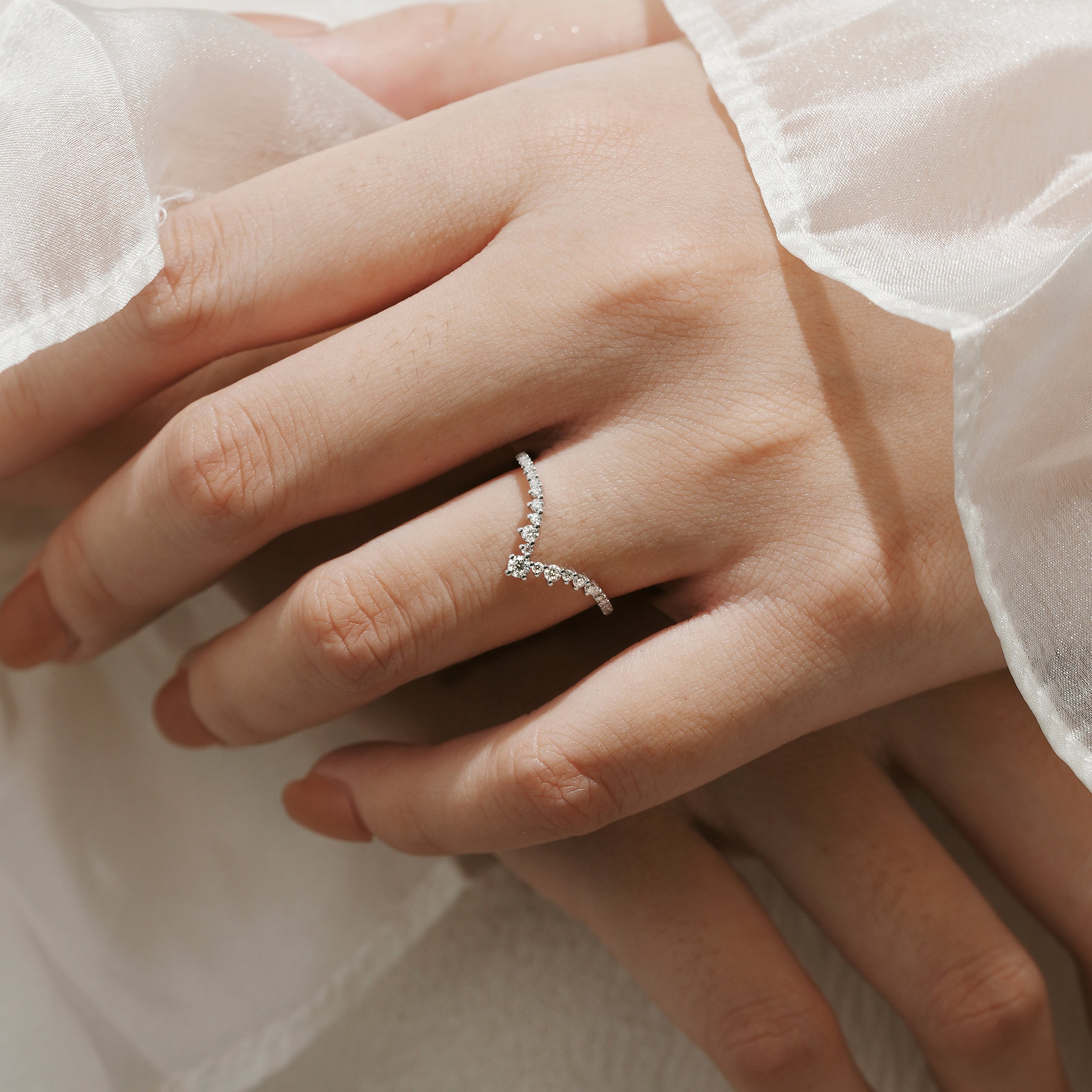 Moissanite V-shaped wedding band on a hand, elegant and minimalist design