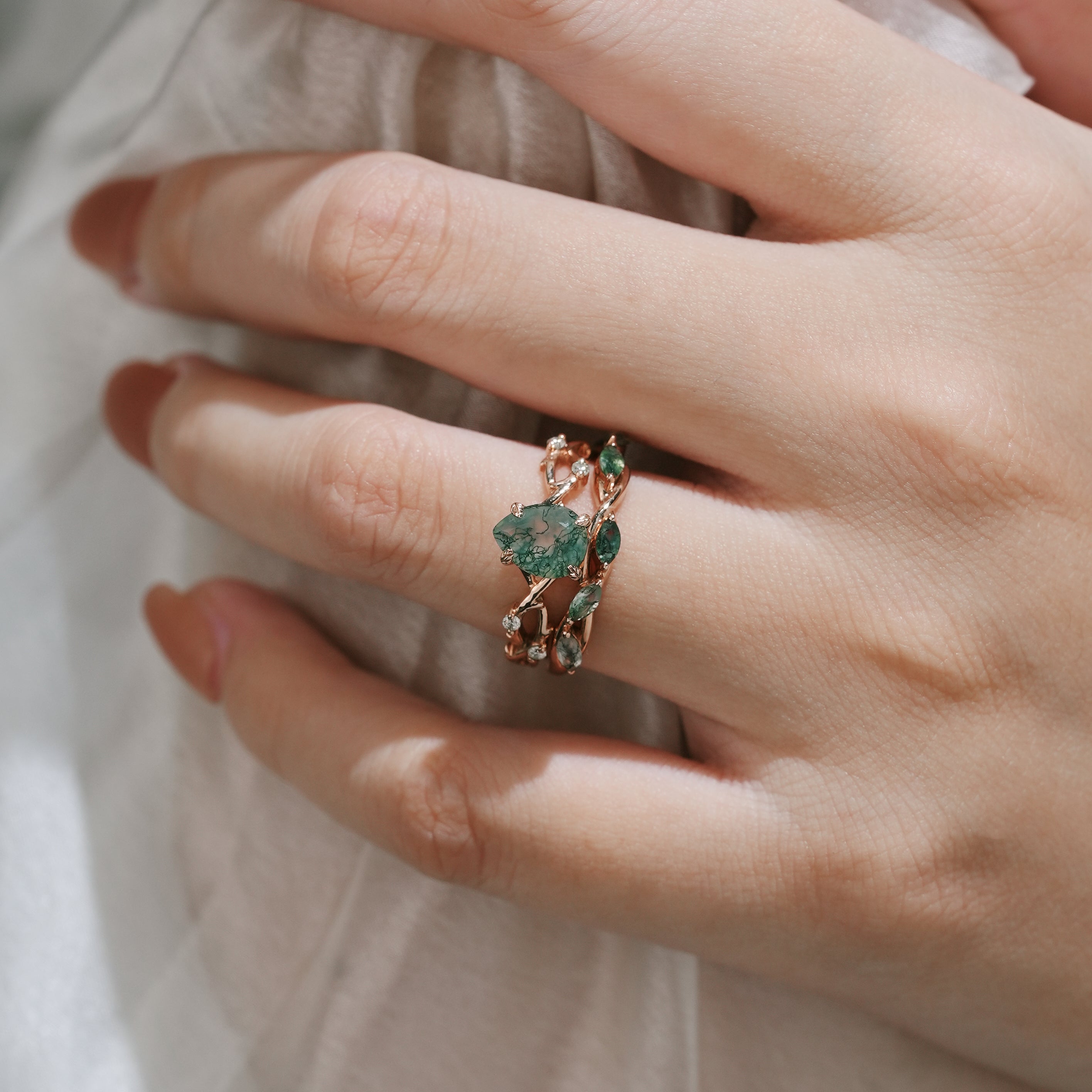 Rose gold moss agate ring set on a hand. Bridal ring set featuring a pear-cut engagement ring and wedding band.