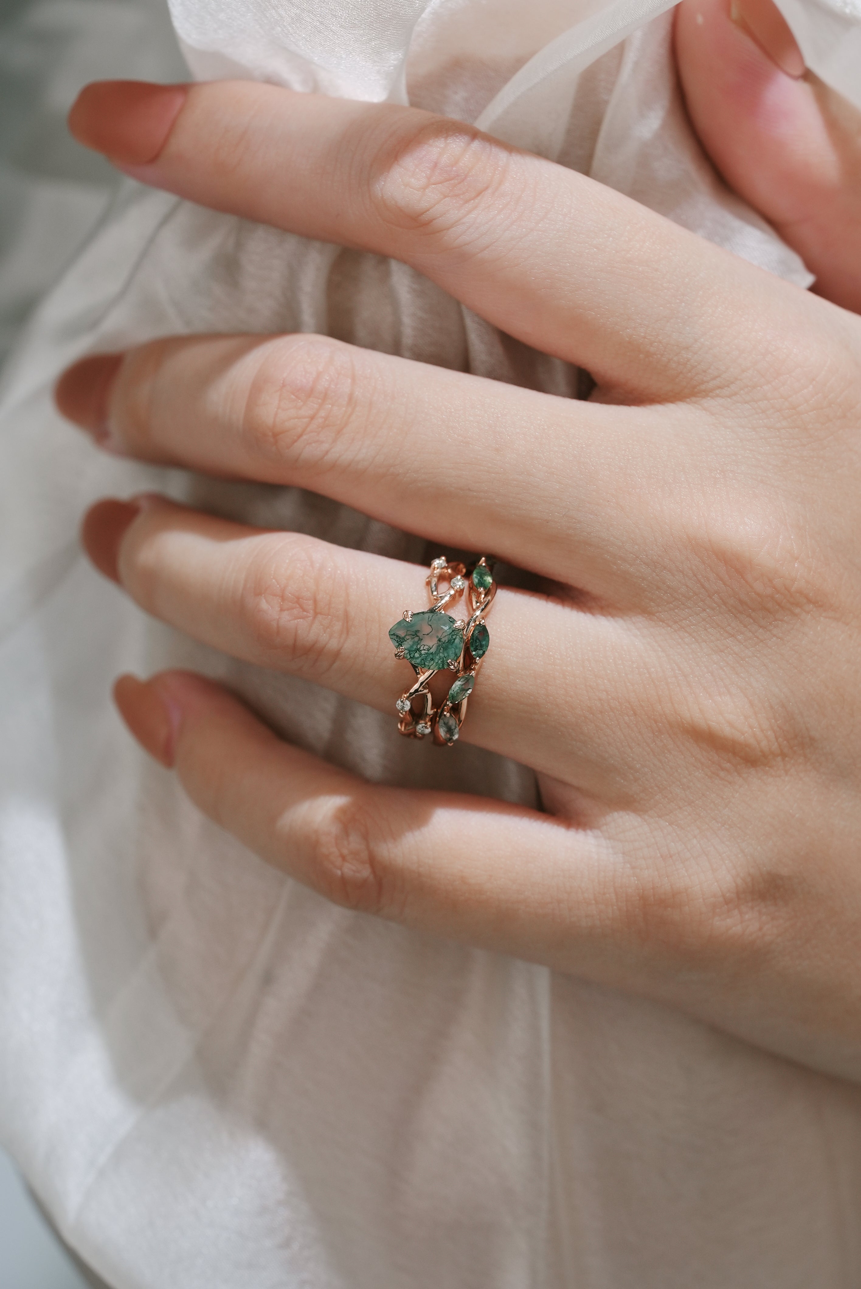 Rose gold moss agate ring set on a hand. Bridal ring set featuring a pear-cut engagement ring and wedding band.