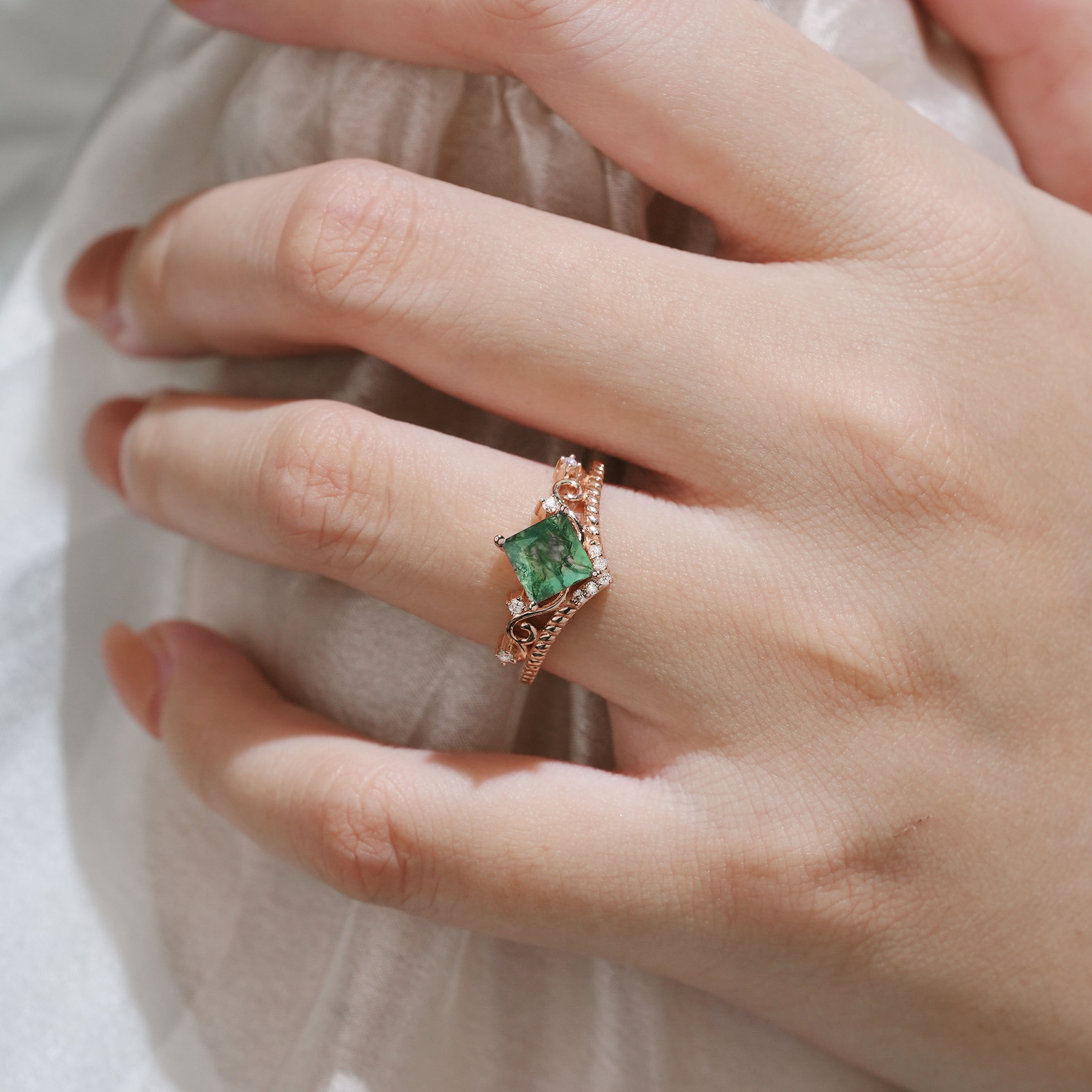 Hand wearing moss agate vintage engagement ring with princess cut