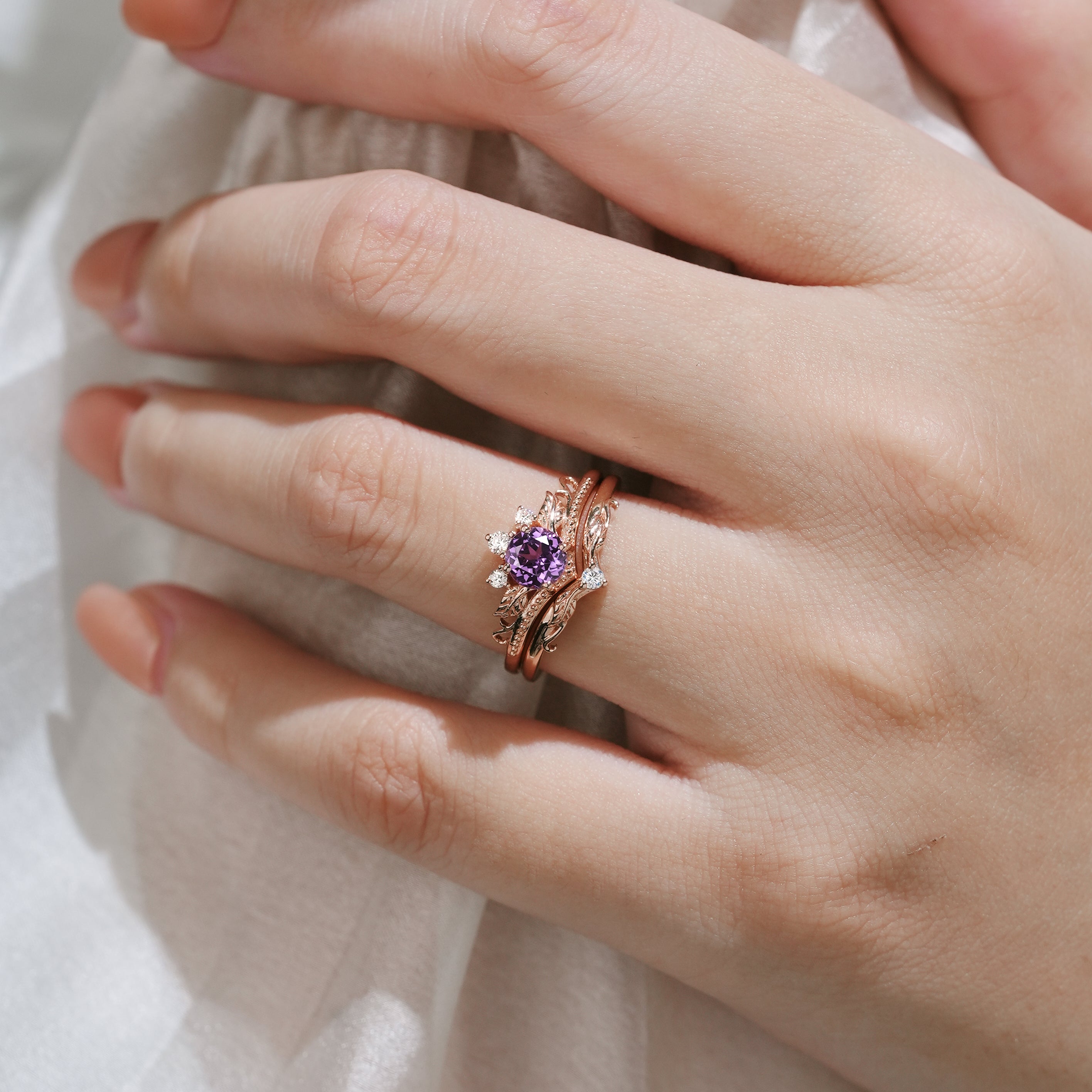 Hand wearing purple sapphire leaf engagement ring set